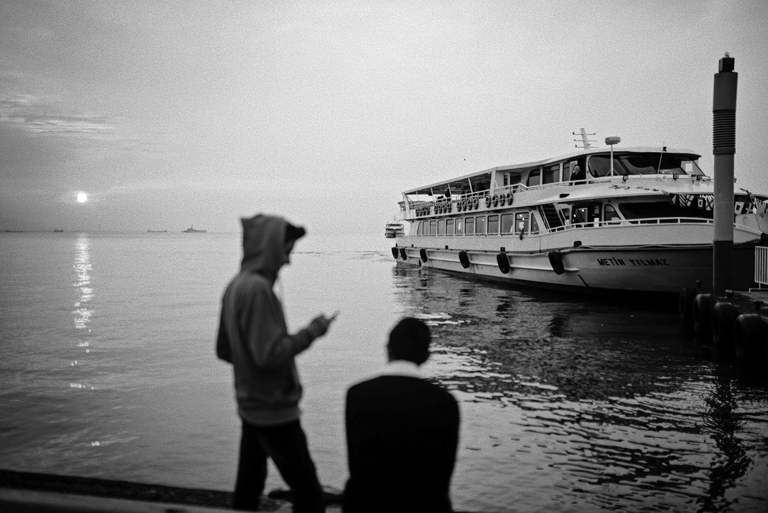 Two teenagers killing time by the Alsancak ferry port in İzmir, Turkiye.
