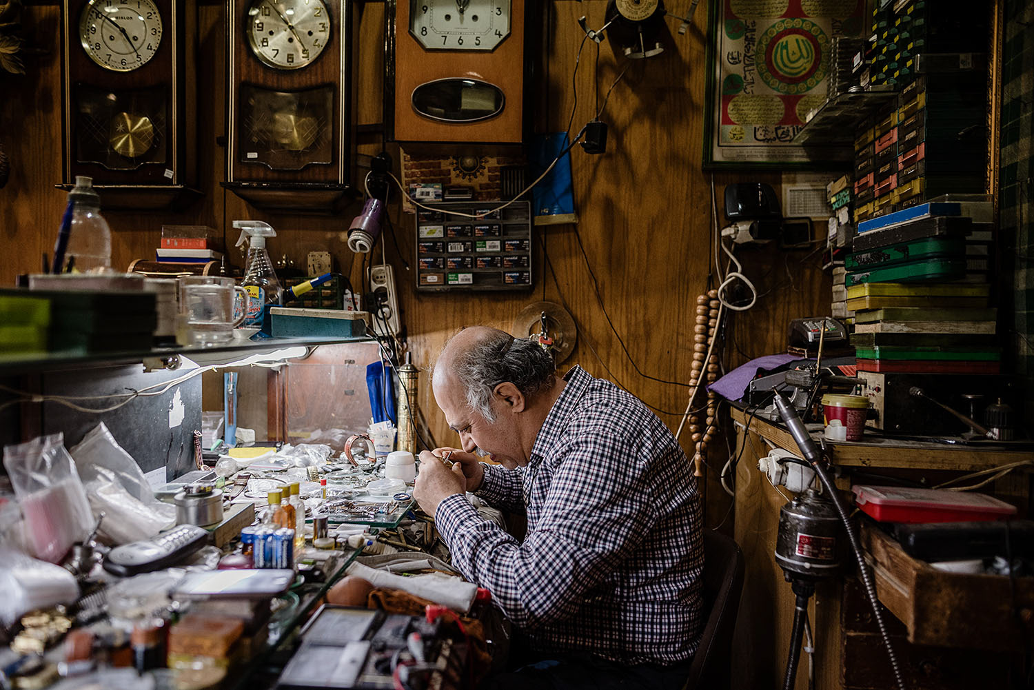 A watch repairman taking a close look at a watch.
