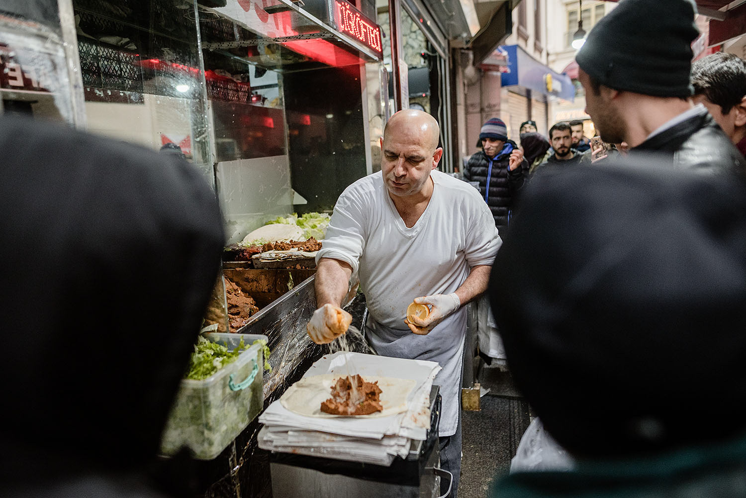 A famous guy, Çiğköfteci Ali Usta, in preparing food in his restaurant in the Grand Bazaar in İstanbul while people watch him.