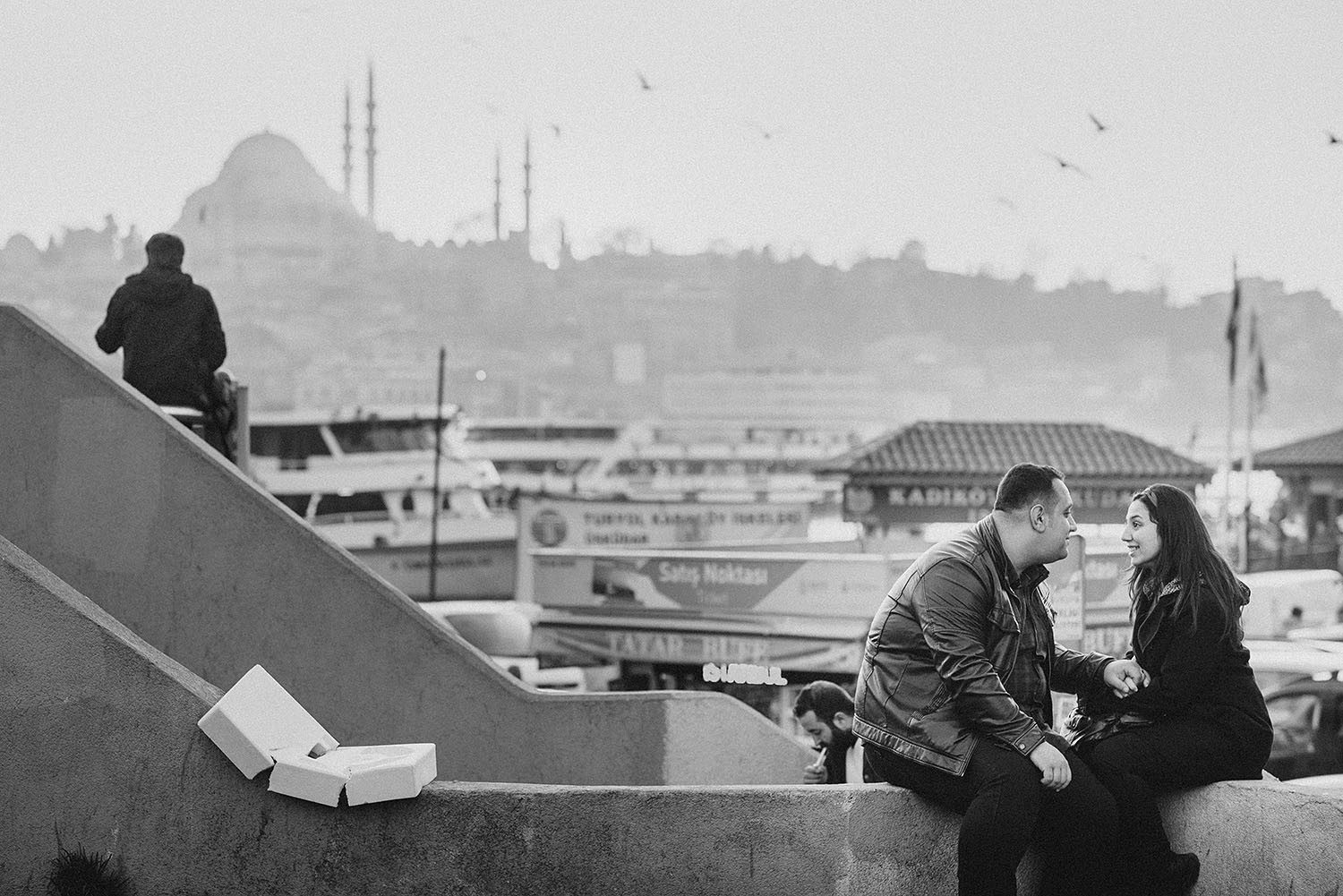 A couple is holding hands and looking at each other in a black and white image.