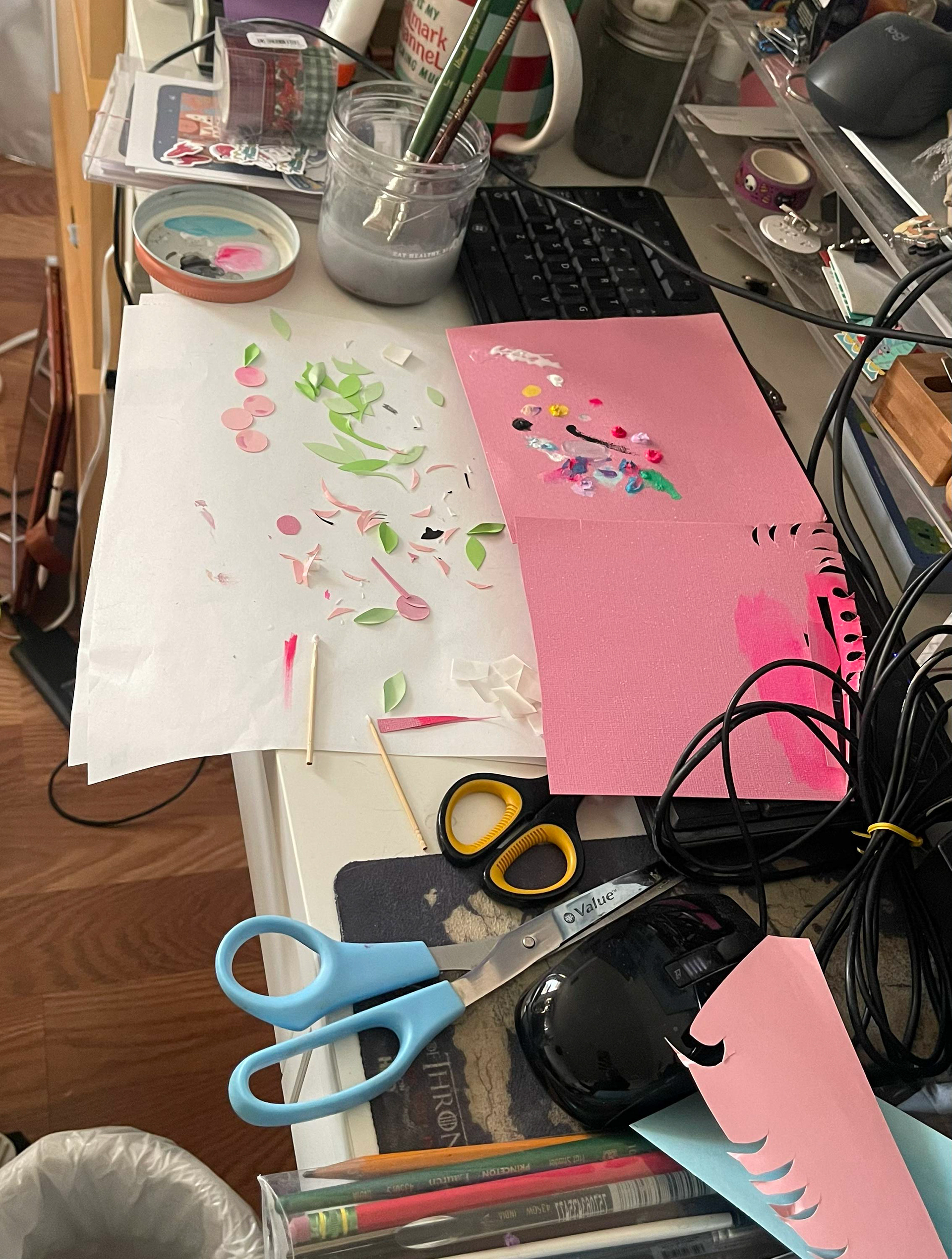 A messy desk of hand cut flowers and hand-painted details