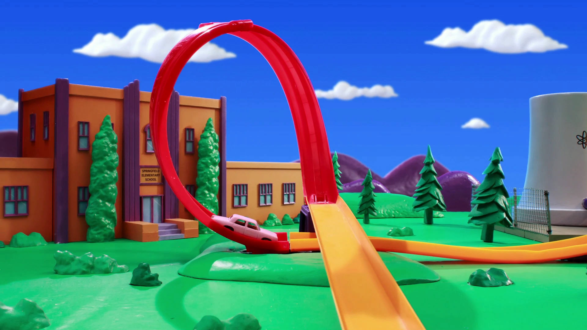 Screen Still - Toy car track w/ school in background
