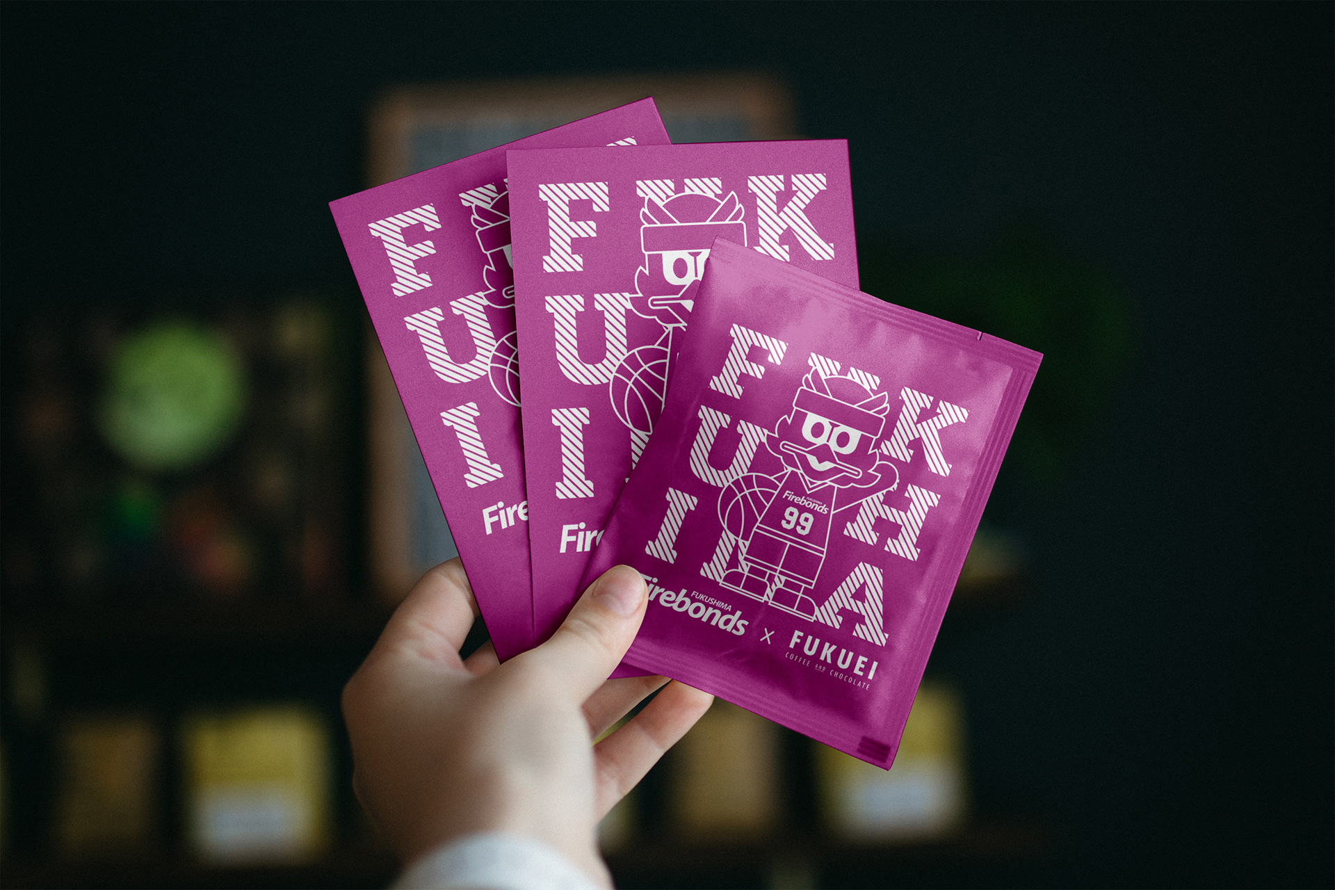 Coffee drip bag packaging illustration and design for the Fukushima Firebonds and Fukuei collaboration, showing a hand holding three vibrant purple sachets featuring white line art mascot graphics and bold typography.