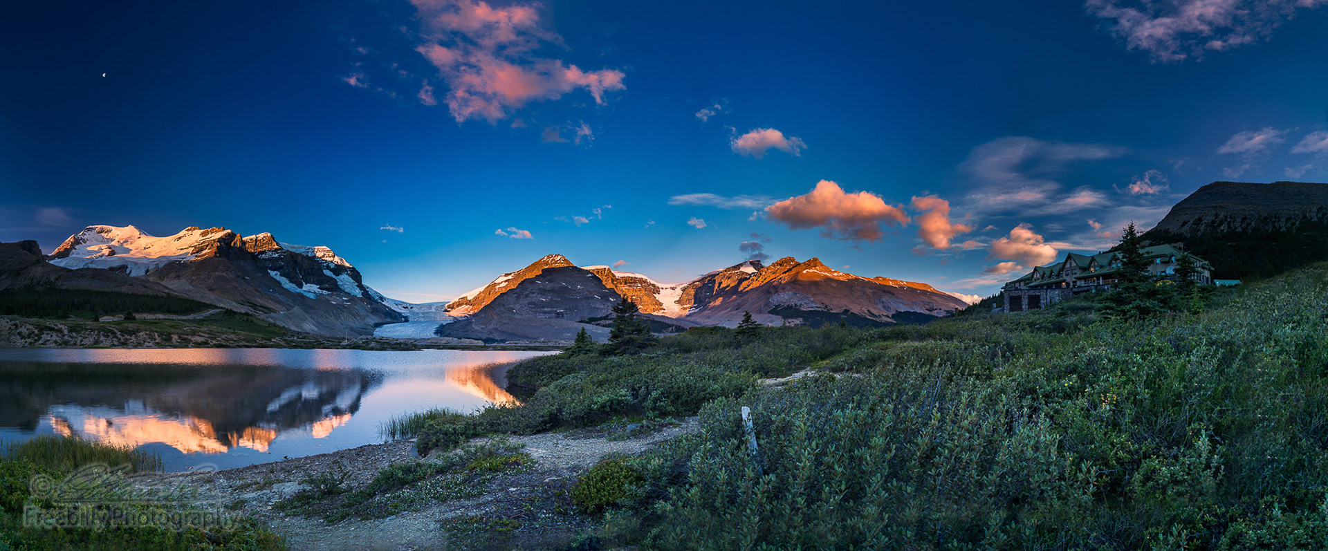 The panoramic view of snowy mountain and colorful clouds with lake reflections at ice field center of Jasper National Park.