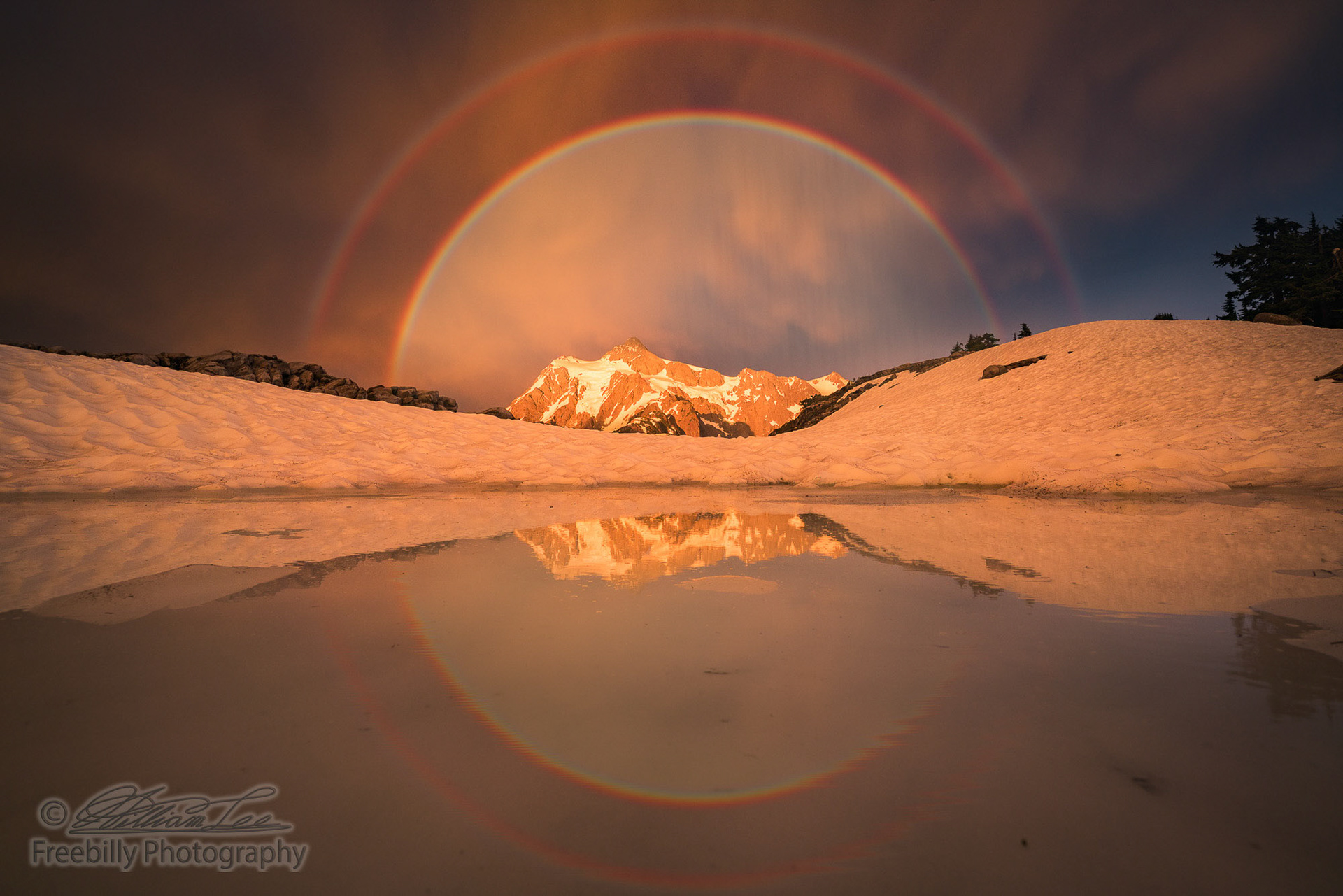 Mt Shuksan illuminated by setting sun with double rainbow and reflections.