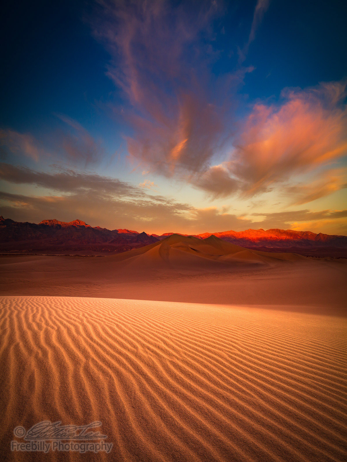 This is a photograph of Death Valley sand dune with colorful clouds in California, USA