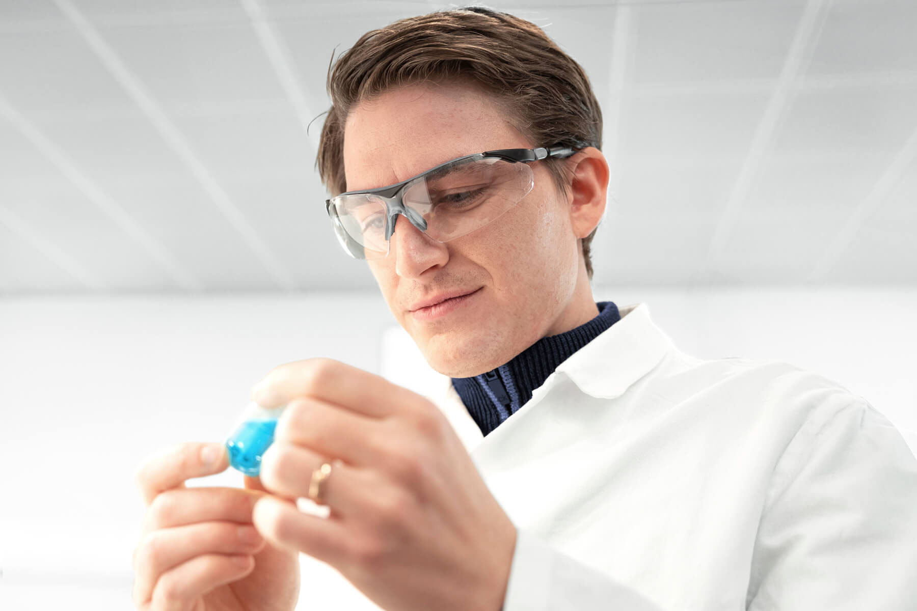 Labormitarbeiter untersucht ein Vial mit Flüssigkeit.
