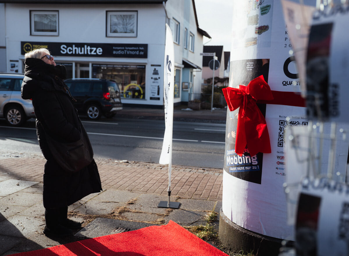 Besucherin schaut die Litfassäule vor der Enthüllung an.