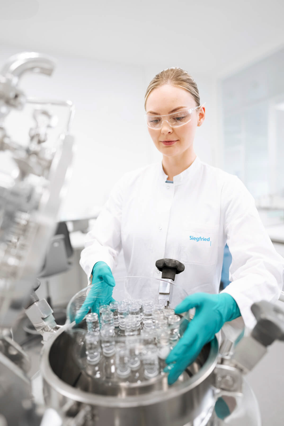 Industriefoto einer Labormitarbeiterin in einem cleanen Laborsetting. Fotografie: © Philipp Eigner, Bildretusche: © SOURCE Associates AG