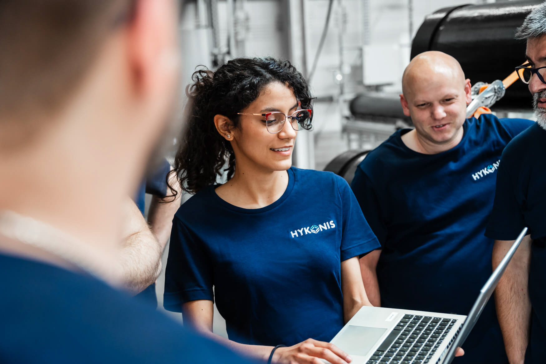 Industrielle Fotografie für Hamburg und Umgebung. Mitarbeitende diskutieren am Laptop in einer Werkhalle.