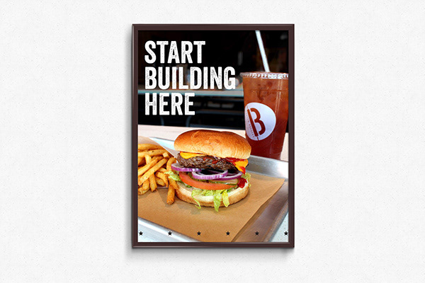 A small printed sign consisting of burger imagery and large type. This sign was used as a starting point for customers to begin ordering their custom burgers in the restaurant.