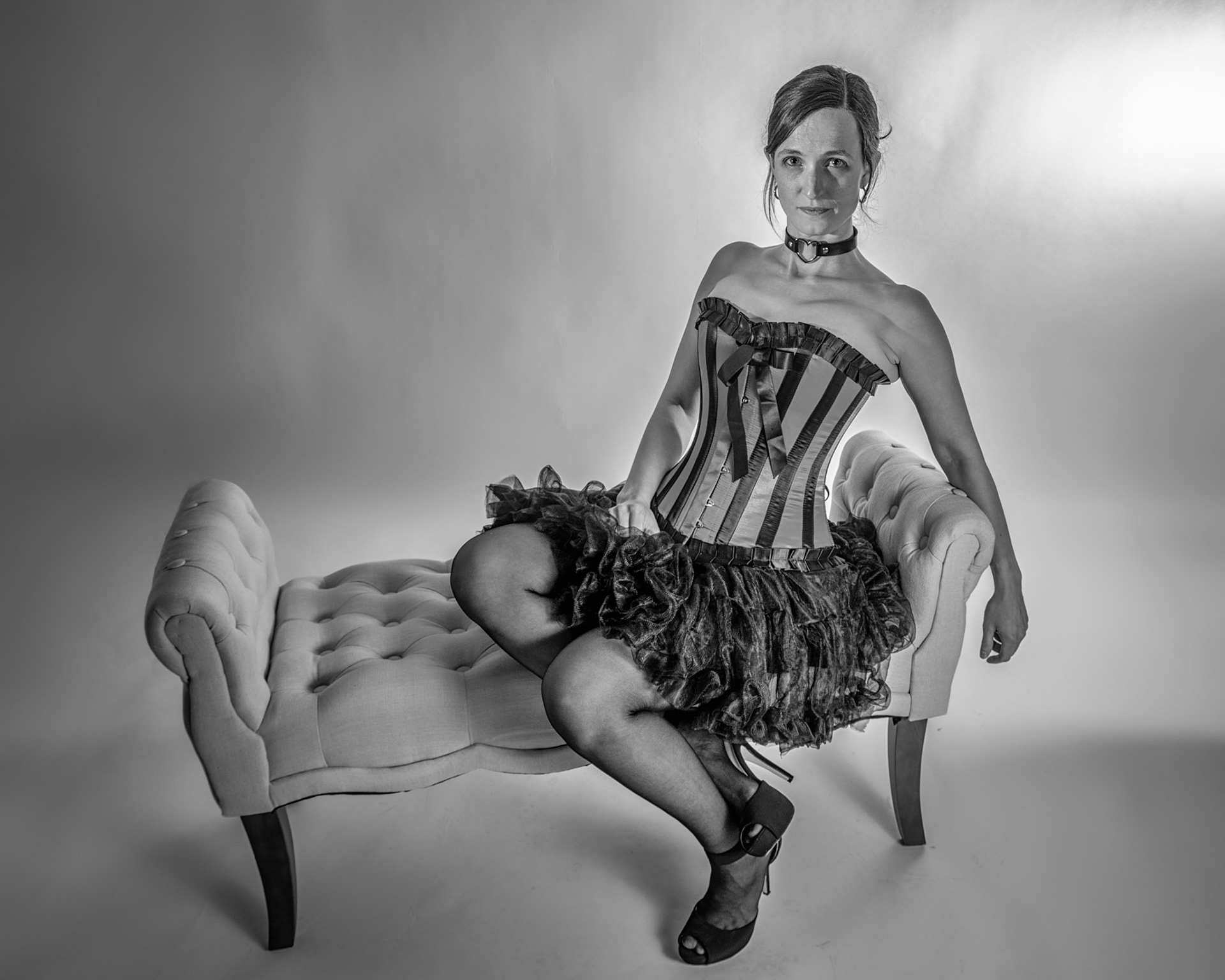 Western Corsetry - Fainting on the Fainting Couch: Bringing back out the western themed corset outfit for a final run at studio shots with the seamless backdrop. Godox v1 with 7" reflector front left, 30x120 softbox with another Godox V1 right side, and Godox AD200 w/ Yellow gel lighting the backdrop.