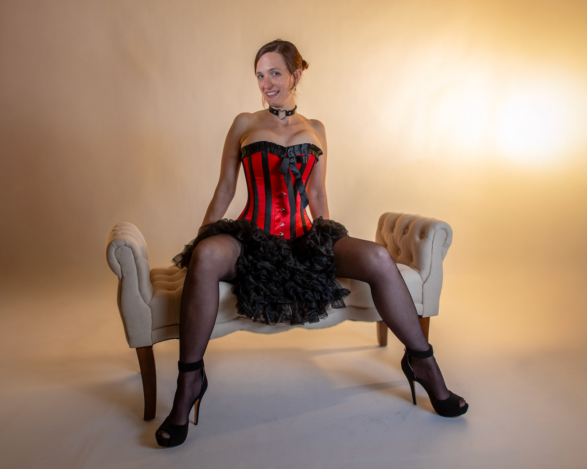 Western Corsetry - Reclining on the Fainting Couch: Bringing back out the western themed corset outfit for a final run at studio shots with the seamless backdrop. Godox v1 with 7" reflector front left, 30x120 softbox with another Godox V1 right side, and Godox AD200 w/ Yellow gel lighting the backdrop.