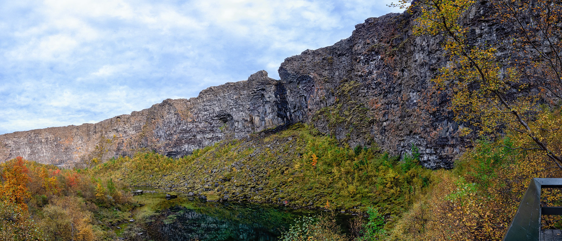 A viewing platform from the side of Asbyrgi, capturing the cliff wall and the pond