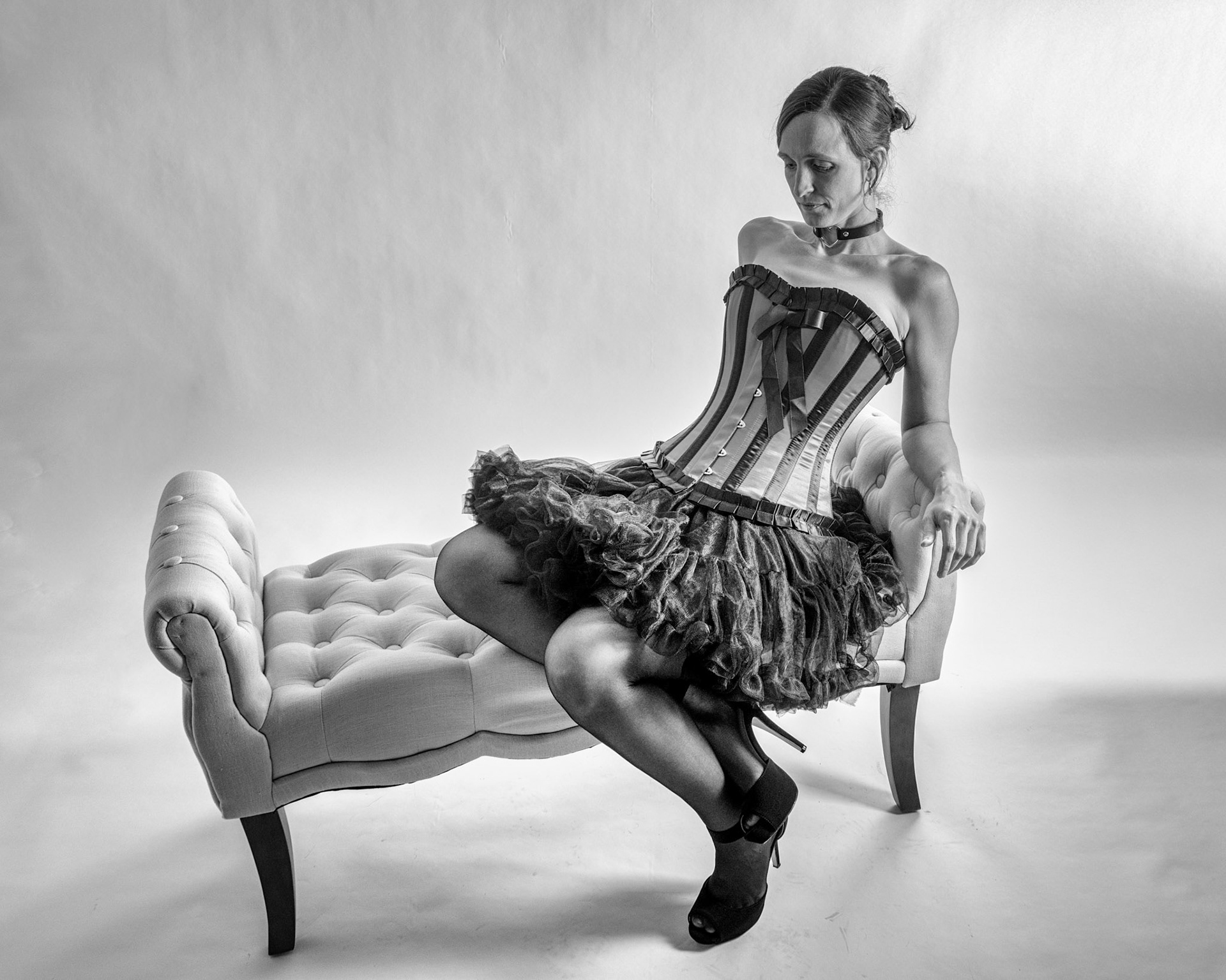 Western Corsetry - Reclined (B&amp;W): Bringing back out the western themed corset outfit for a final run at studio shots with the seamless backdrop. Godox v1 with 7" reflector front left, 30x120 softbox with another Godox V1 right side, and Godox AD200 w/ Yellow gel lighting the backdrop.
