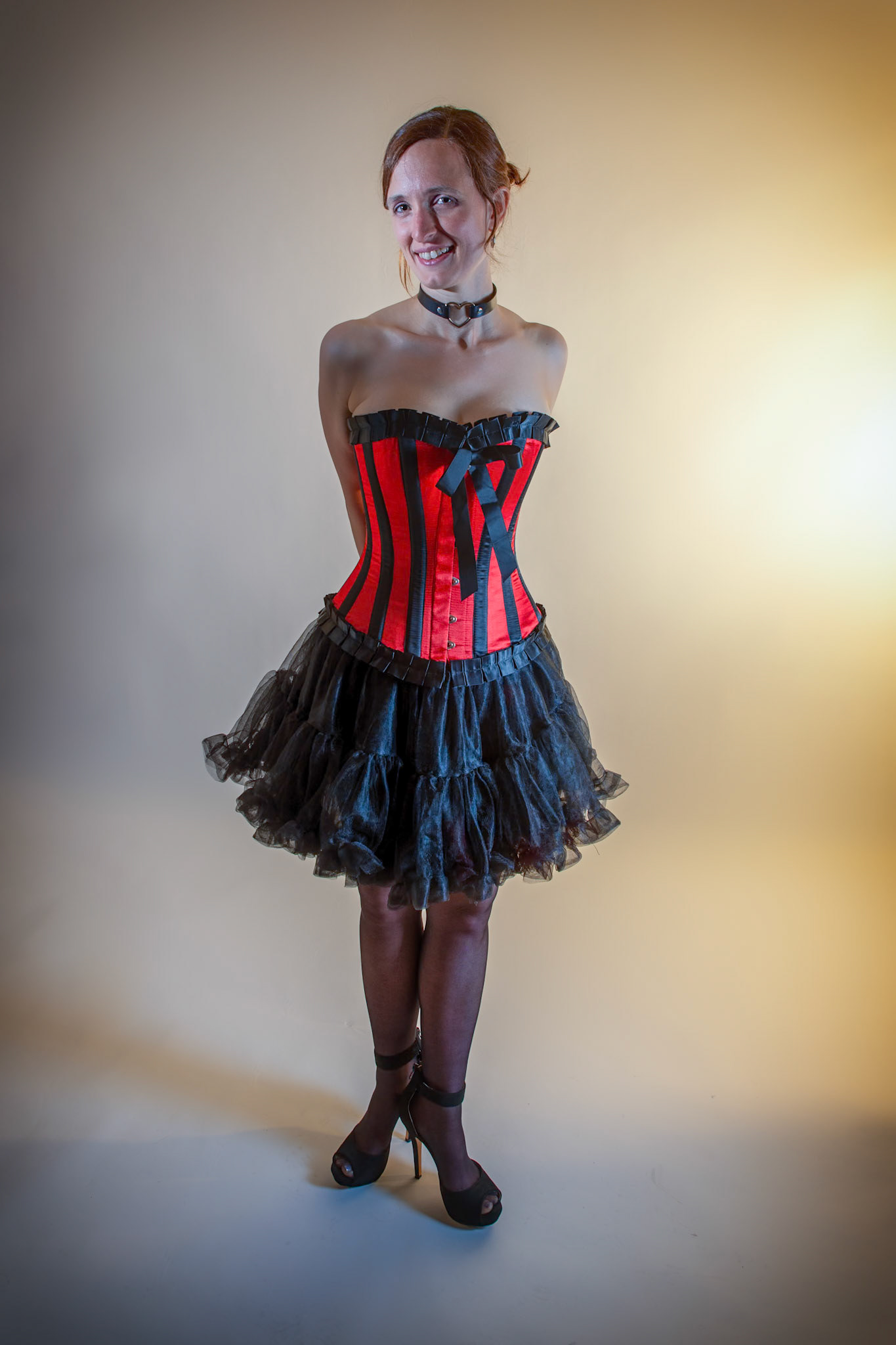 Western Corsetry - Ankles Crossed: Bringing back out the western themed corset outfit for a final run at studio shots with the seamless backdrop. Godox v1 with 7" reflector front left, 30x120 softbox with another Godox V1 right side, and Godox AD200 w/ Yellow gel lighting the backdrop.