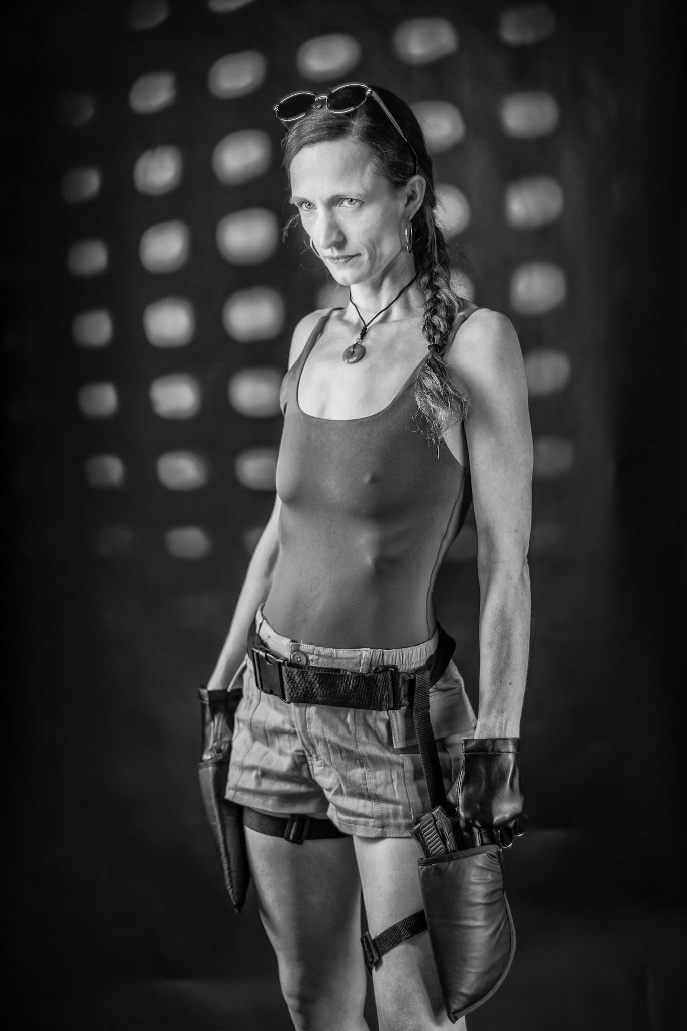 Lara Croft: Tactical Readiness (B&amp;W): Textures of leather, fabric, and skin are brought into high relief through precise studio lighting. The abstract background provides a cinematic depth that elevates the iconic adventurer aesthetic into the realm of fine art.