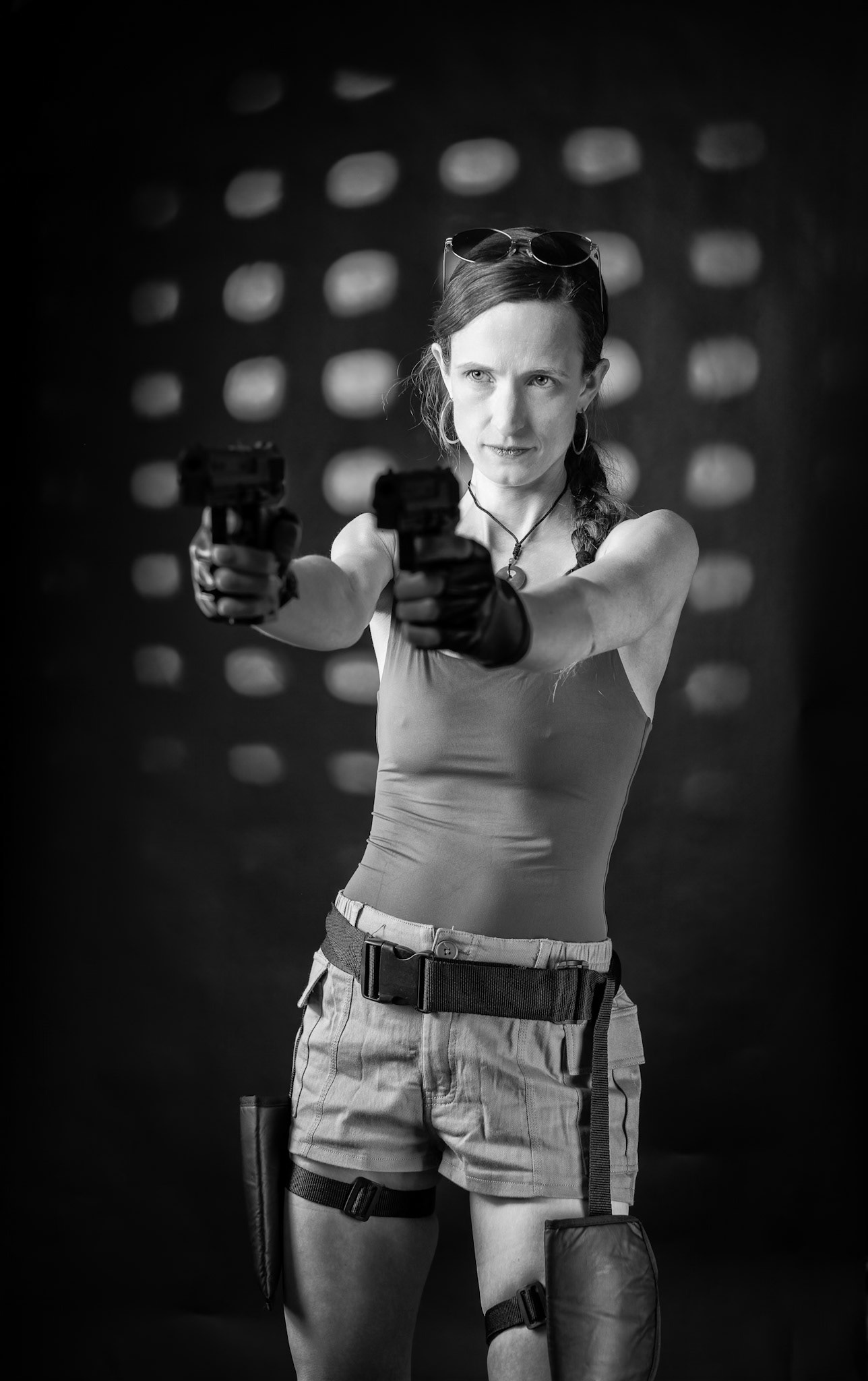 Lara Croft: Locked on Target (B&amp;W) - A cinematic Lara Croft cosplay portrait inspired by Tomb Raider. With dual pistols drawn and eyes locked forward, this studio setup captures the intensity and confidence of the iconic adventurer. Custom 3D-printed prop weapons and dramatic rim lighting add depth and tension, bringing the action-game energy into a controlled studio environment.Lit with a Flashpoint XPlor 600 key, Godox AD200/V1-P fill, and a gobo backlight for that signature cinematic edge.