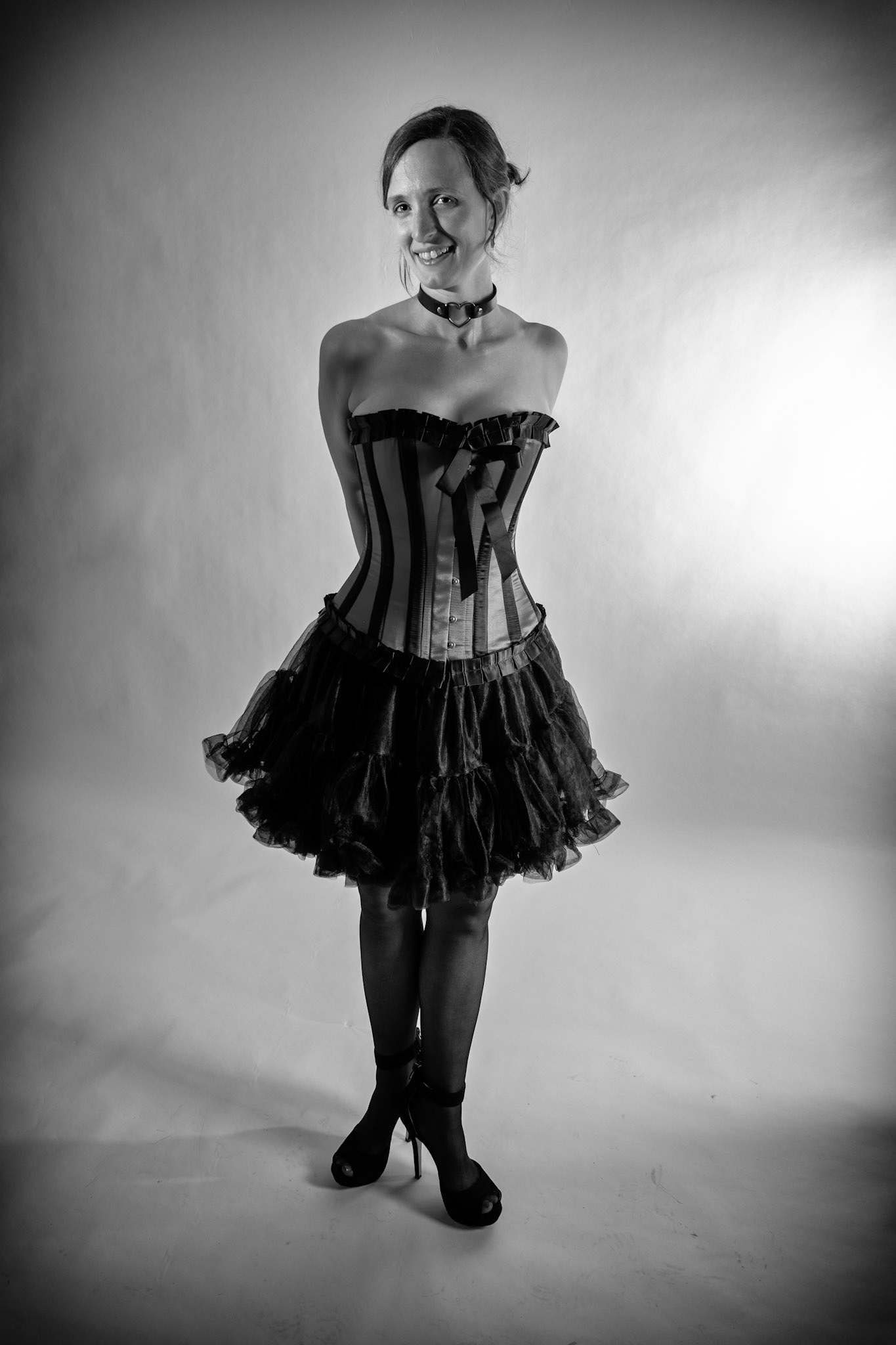 Western Corsetry - Ankles Crossed (B&amp;W): Bringing back out the western themed corset outfit for a final run at studio shots with the seamless backdrop. Godox v1 with 7" reflector front left, 30x120 softbox with another Godox V1 right side, and Godox AD200 w/ Yellow gel lighting the backdrop.