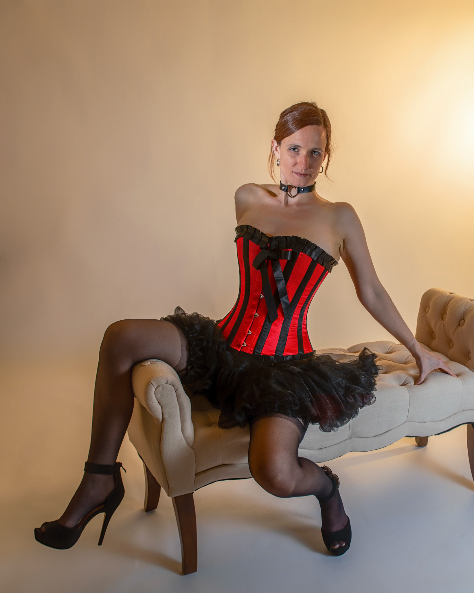 Western Corsetry - Fainting on the Fainting Couch: Bringing back out the western themed corset outfit for a final run at studio shots with the seamless backdrop. Godox v1 with 7" reflector front left, 30x120 softbox with another Godox V1 right side, and Godox AD200 w/ Yellow gel lighting the backdrop.