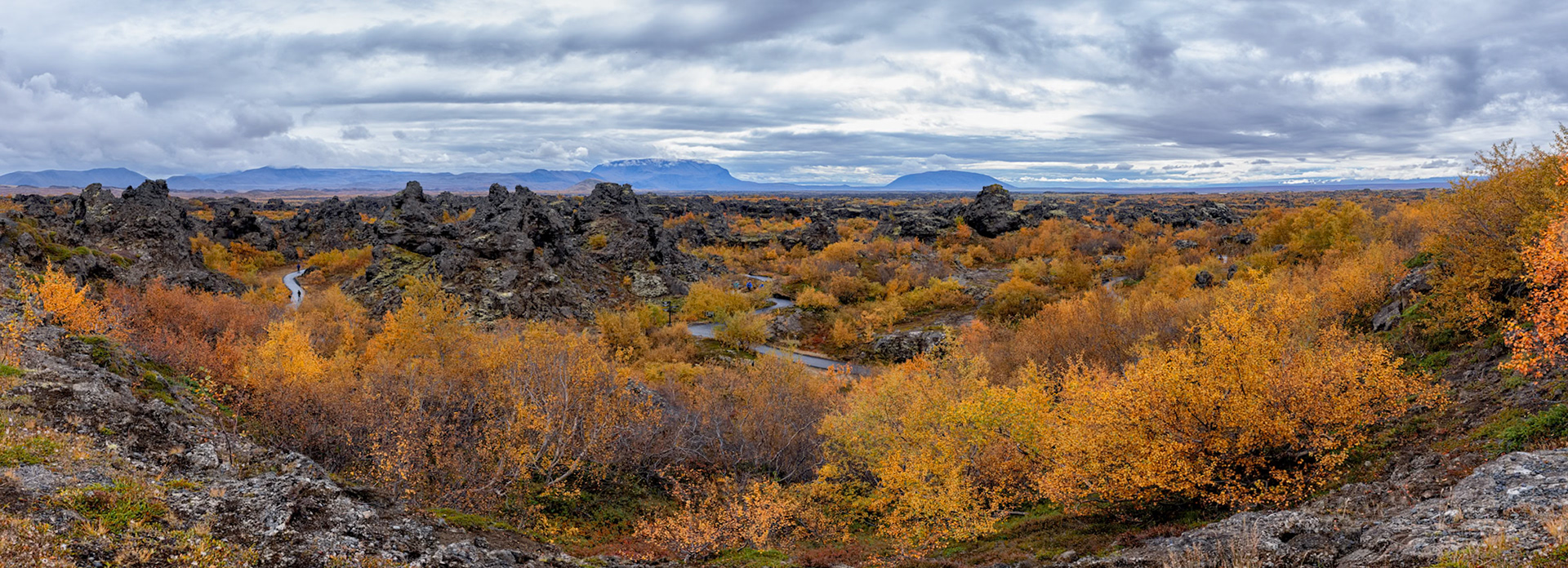 View from the entrance of Dimmuborgir looking into the lava formations. The formation of these extraordinary lava cliffs and pillars stems from molten lava flowing over a pond in the eruption of Lúdentaborgir and Þrengslaborgir some 2300 years ago. The molten lava trapped the water underneath and steam issued through vents in the lava and formed these pillars, which then remained standing even after the pond and the crust around them had disappeared.