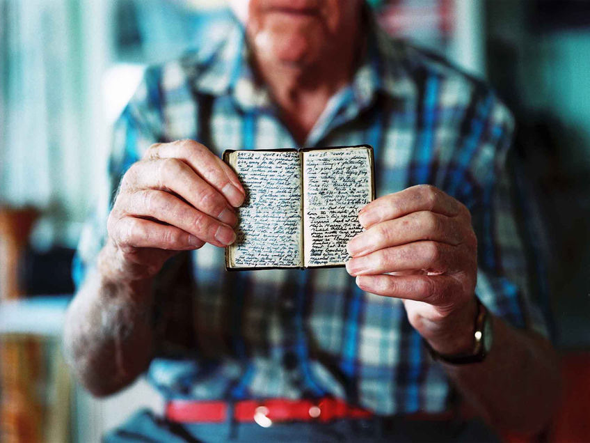 Photographed in his home in Ely at the age of 94, John Lowe shows me his prison diary. Fashioned himself from acquired materials, this miniature act of defiance would have cost him his life if found, but is now a valuable record. At the time of this photograph, John was Britain’s oldest ballet dancer, having taken it up at the age of 80 years old.