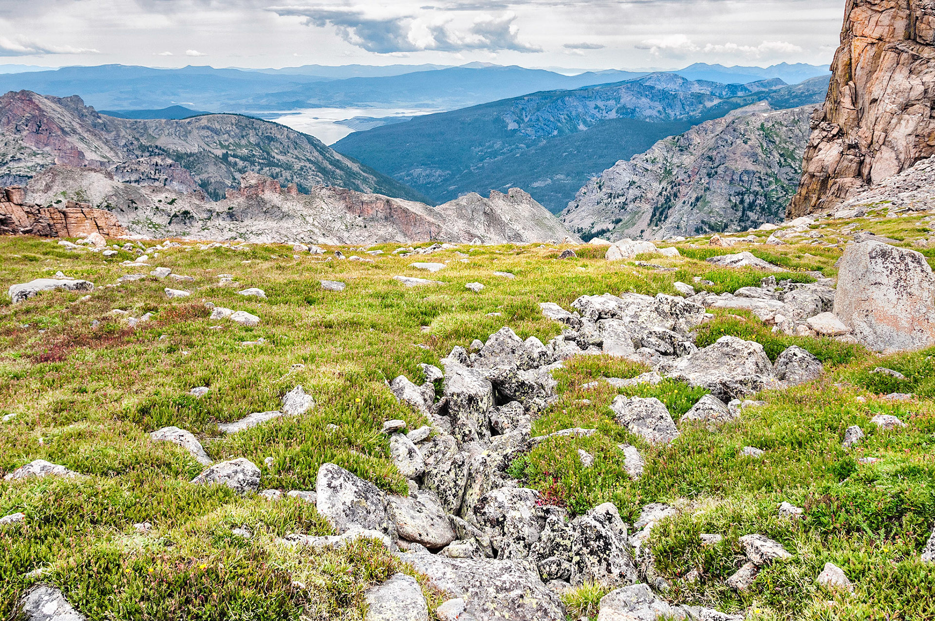 Grand Lake, the largest natural lake in Colorado, USA, (at 8,369 feet = 2,551 m), shimmers in the distance under cloudy skies. Also viewed here, is the tundra and scree terrain at Pawnee Pass, (12,542 ft = 3,823 m), on the Rocky Mountain Continental Divide in the Indian Peaks Wilderness Area.