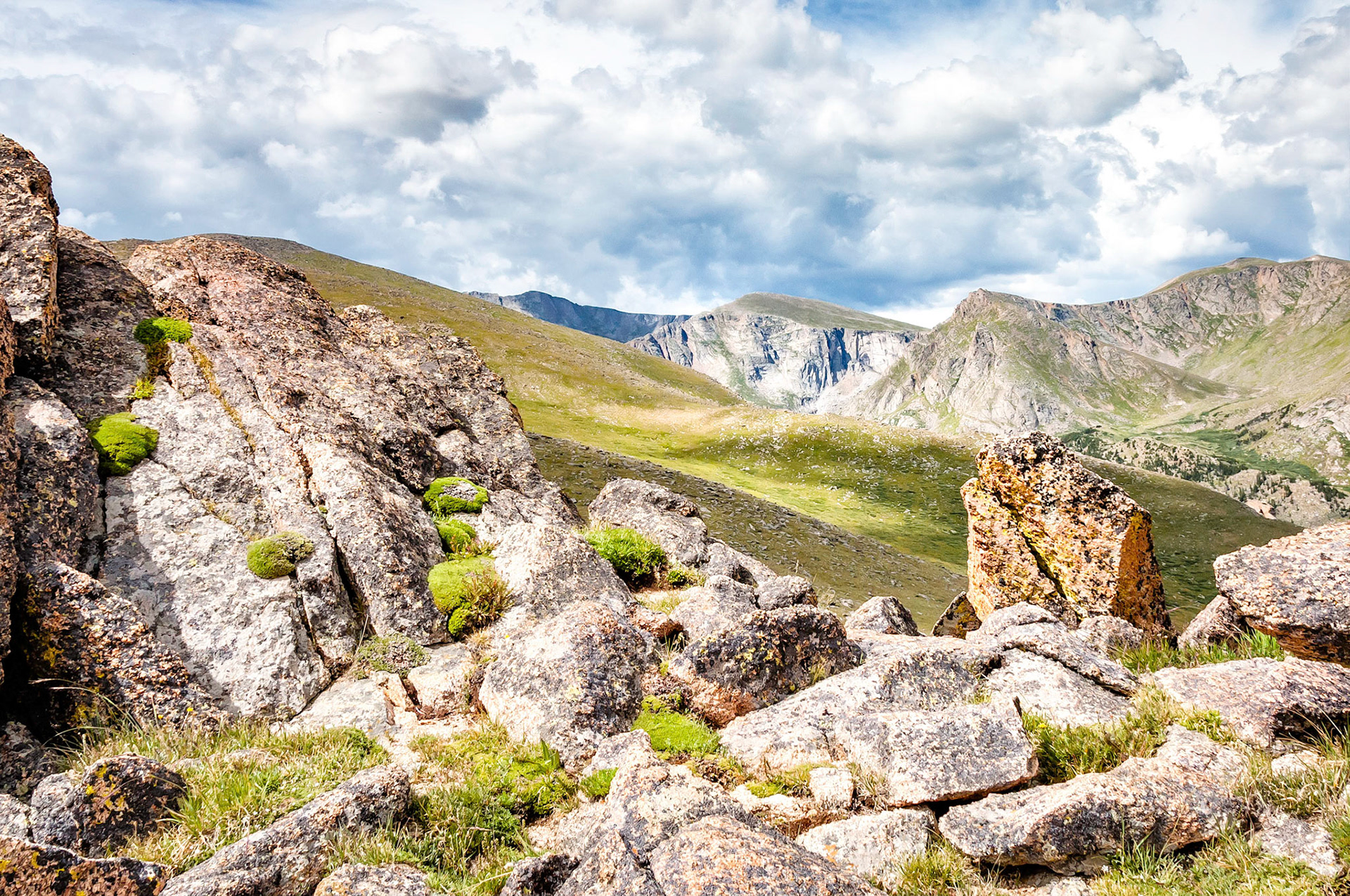 High above timberline, passing clouds cast their shadows over the tundra fields that undulate among the rocky cliffs of the Mountain Evans Wilderness Area near Denver, Colorado, USA.