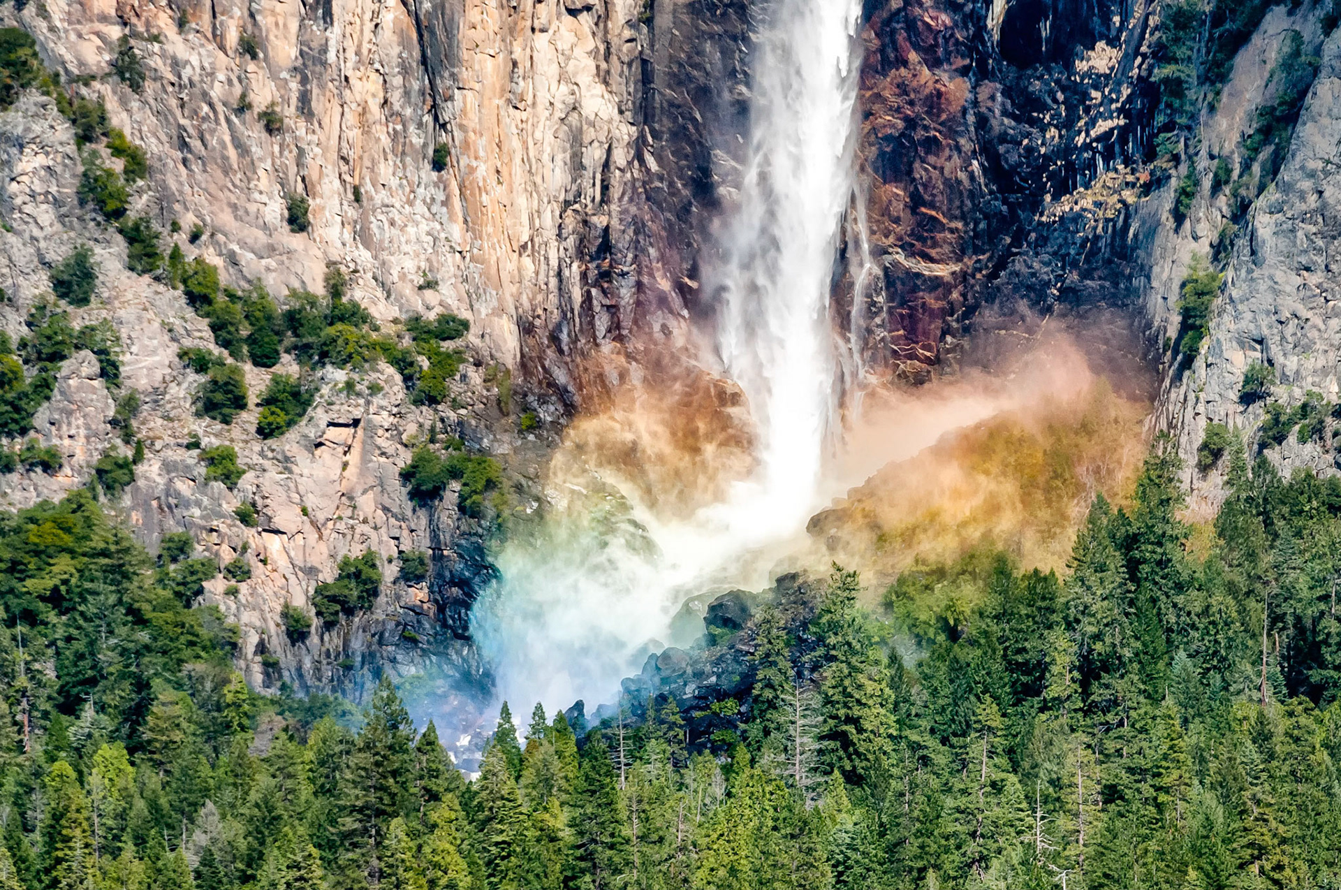 After plunging over 600 feet, (186m), spring snowmelt waters atomize as they pound the rocks below. The afternoon sun is refracted by the mist, forming a fascinating rainbow at the base of the falls.