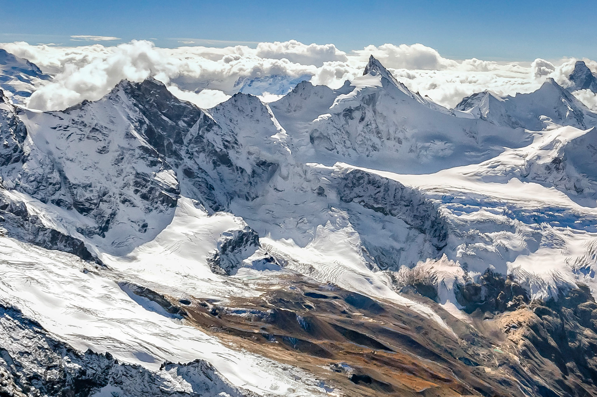 Formed by glacial action, this Swiss alpine skyline rises dramatically against the distant clouds of an incomming storm. Zermatt lies in the valley beyond the rugged ridgeline. The top of the iconic Matterhorn peaks through the clouds on the far right of the image.