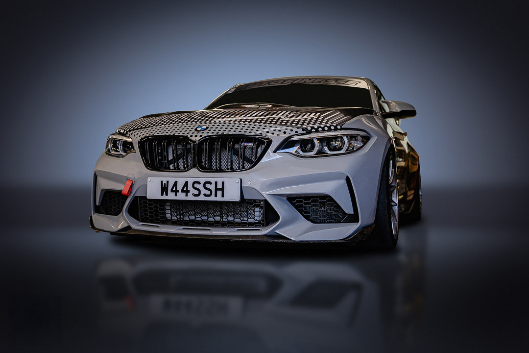 Advanced retouching of a custom white BMW M2  Competition featuring precise color correction and texture refinement of a camouflage pattern on the hood. This technical studio portrait highlights sharp reflections and clean detail enhancement. Specialist modified automotive imagery by Arcane Media