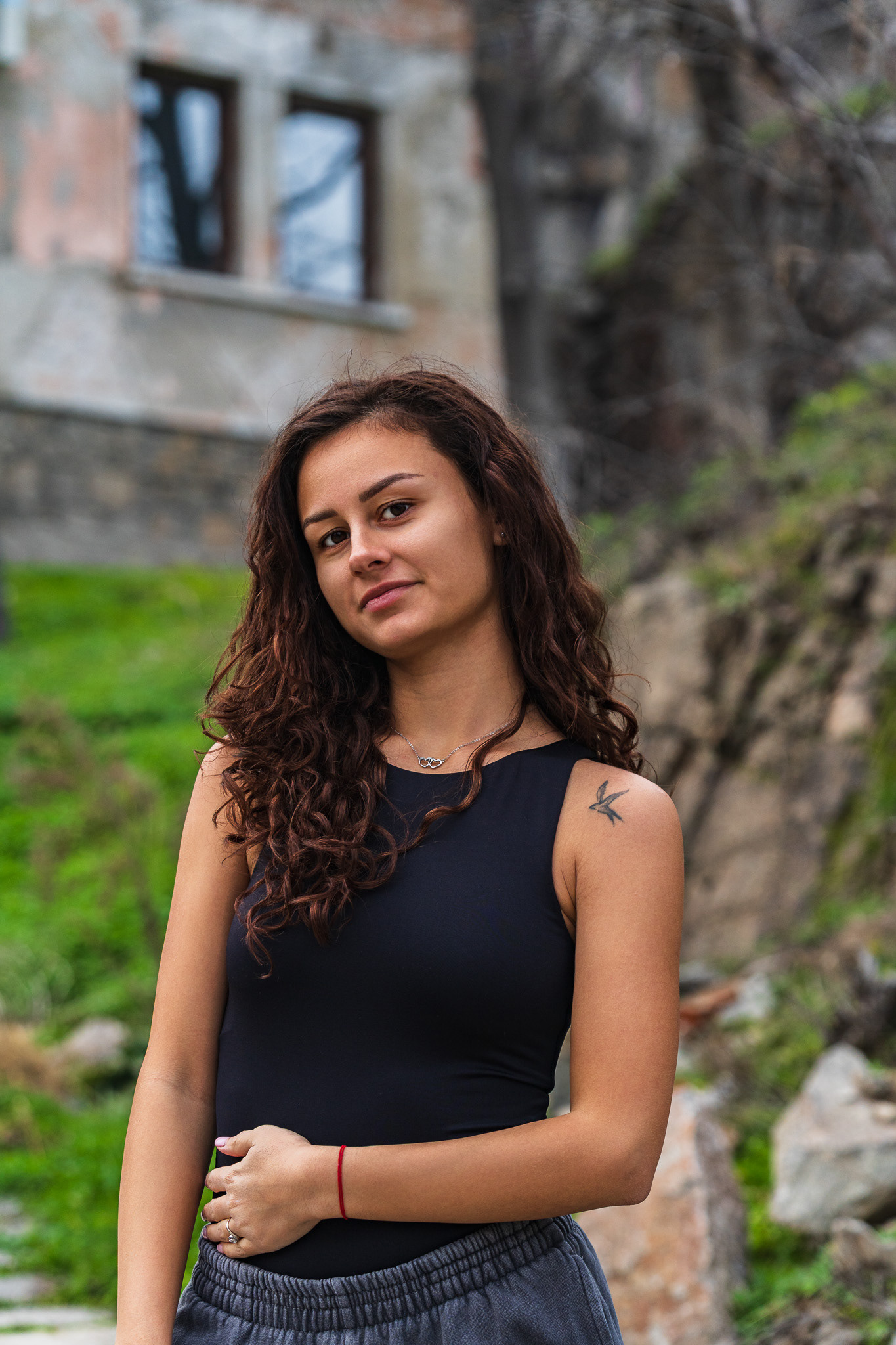 Editorial outdoor portrait of a brunette female model on a stone pathway with green hillside background. Natural light photography by Arcane Media.