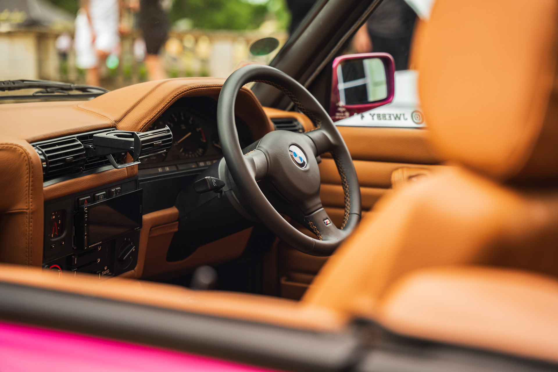 Car interior shot of BMW e30 with steering wheel and dashboard in warm tones