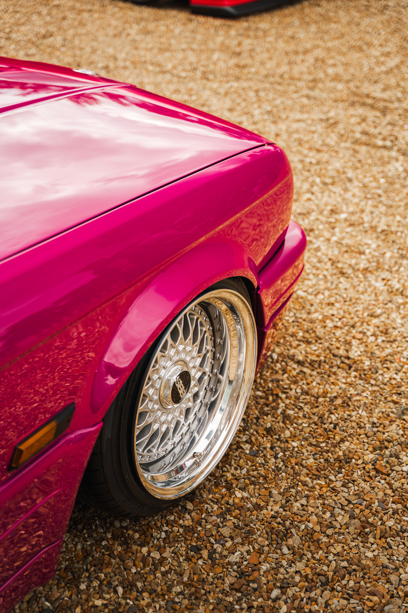 Close-up of pink BMW e30 BBS wheel and paint finish with reflections