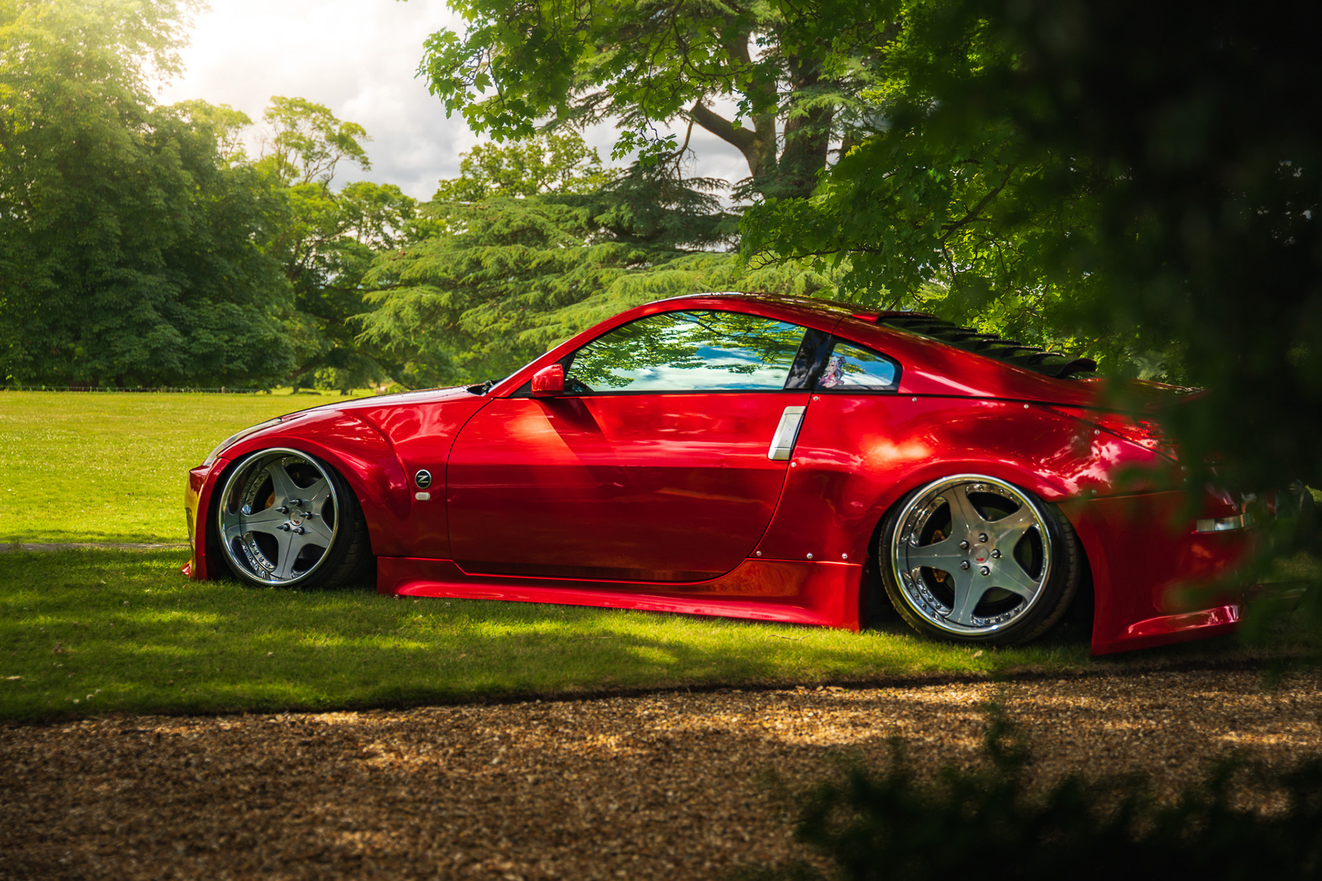 Side profile of red Nissan 350z with lowered stance in outdoor setting