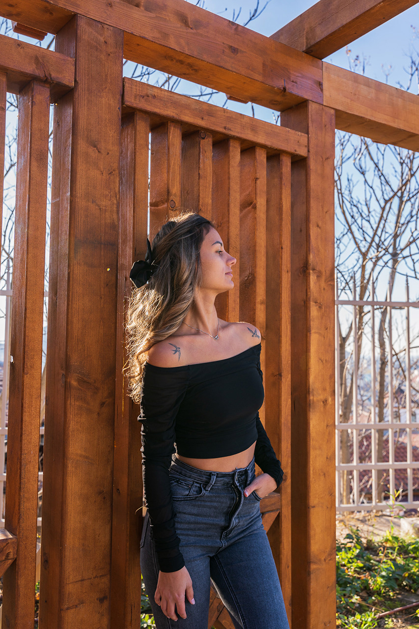 Golden Hour fashion photography featuring a model framed by a wooden pergola. Soft backlighting creates an ethereal, high-end lifestyle aesthetic.