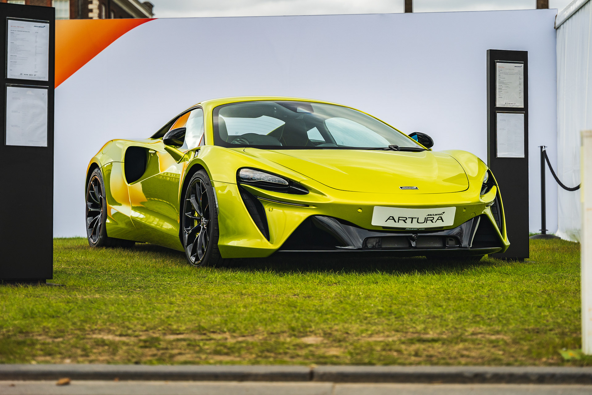 Green car McLAren Artura parked inside modern garage with reflective floor