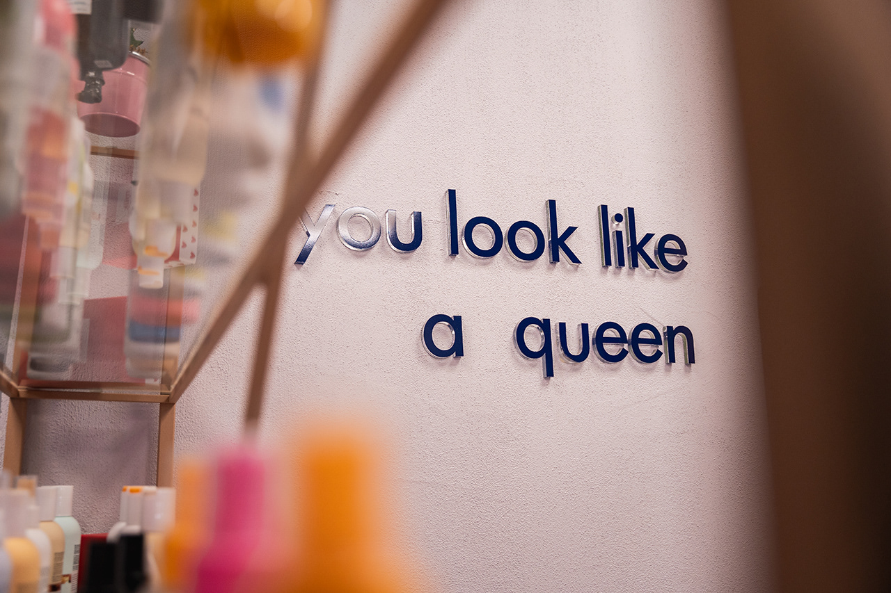 Branding-focused detail shot of salon wall art reading 'You look like a queen.' Capturing the motivational and luxury brand identity of a modern beauty business.
