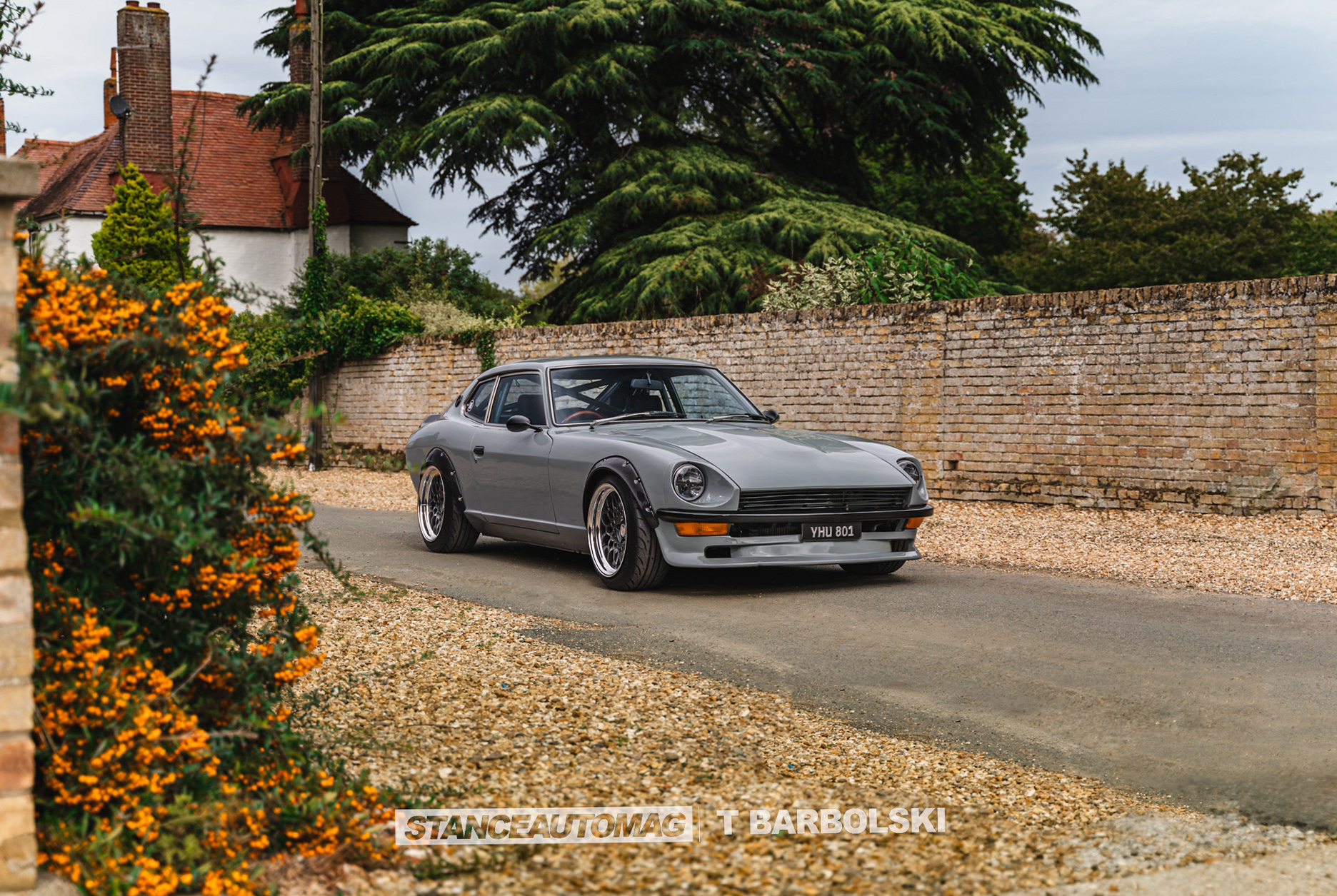 Vintage Datsun 240z on gravel driveway with natural framing and depth