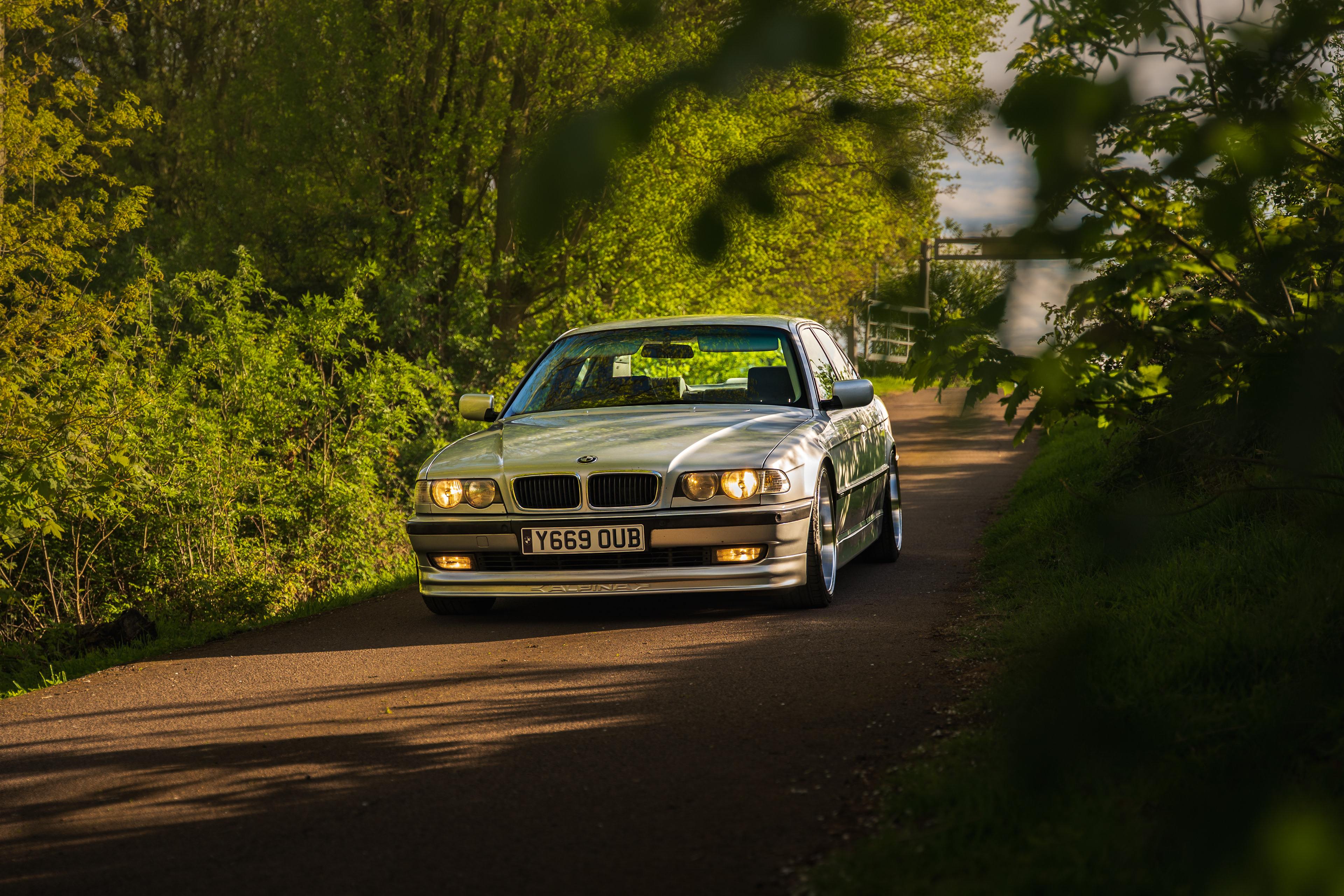 BMW 7 series e38 driving through countryside road with natural light and motion feel