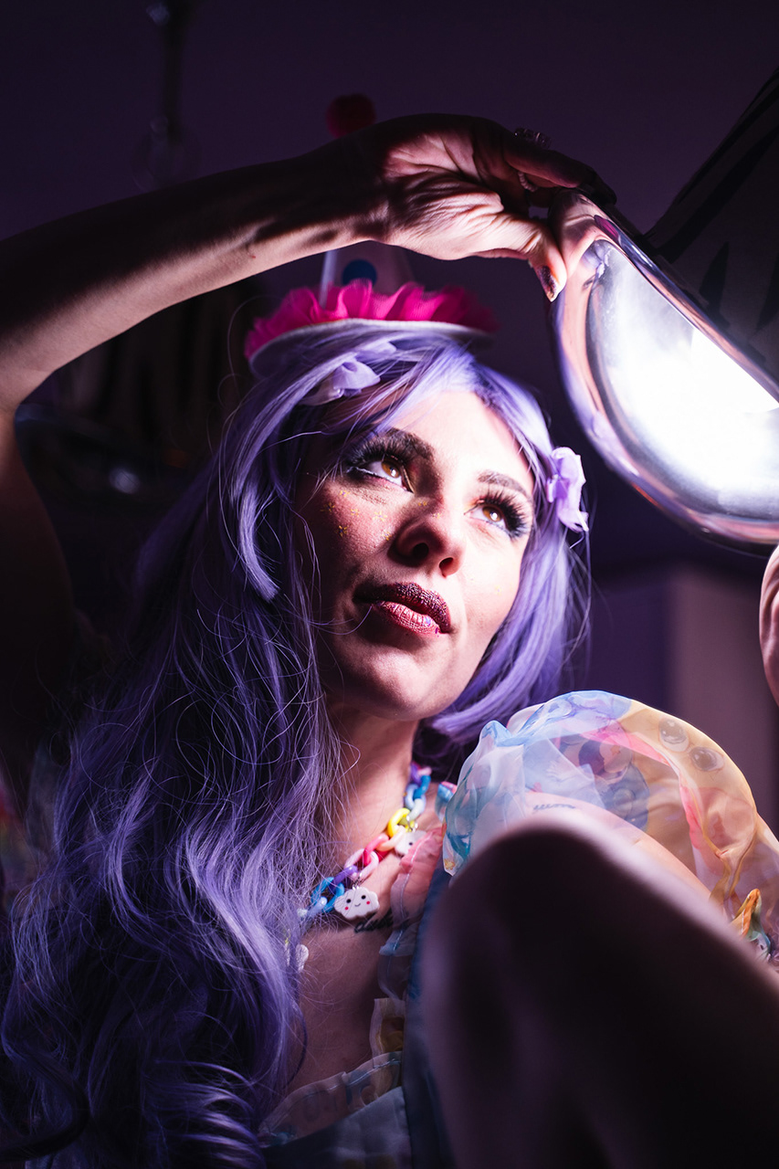 Intense macro beauty portrait of a cosplayer with purple hair and intricate face jewels, utilizing dramatic low-light to isolate the gaze. Fine art conceptual photography by Arcane Media.