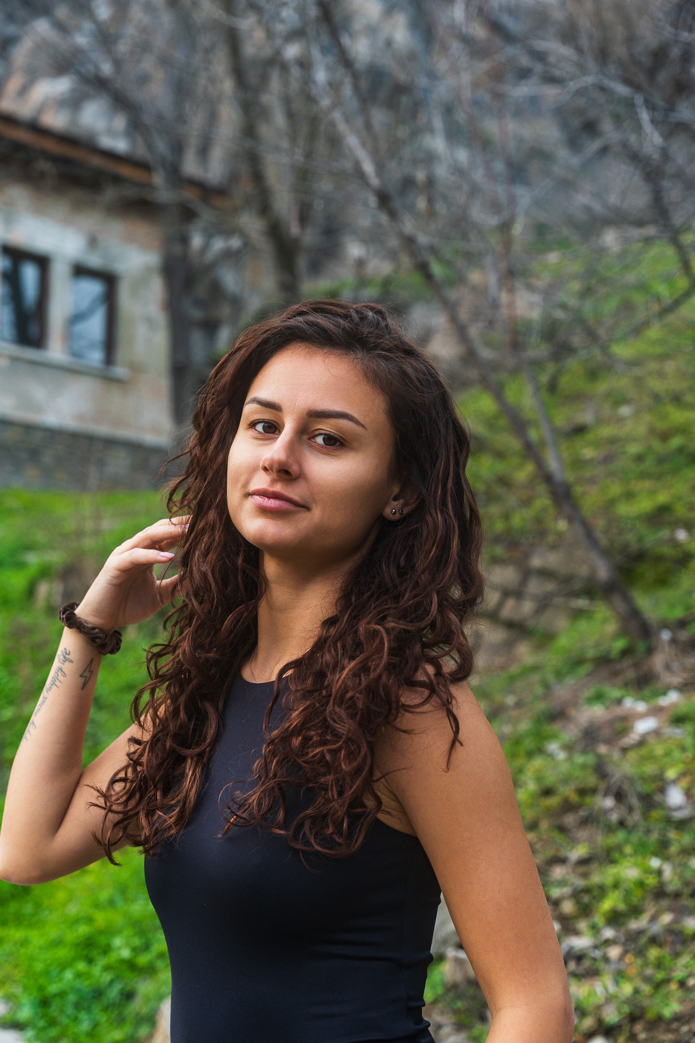 Lifestyle portrait of a female model in a black top with natural curly hair against an Eastern European architectural backdrop. Photography by Arcane Media.