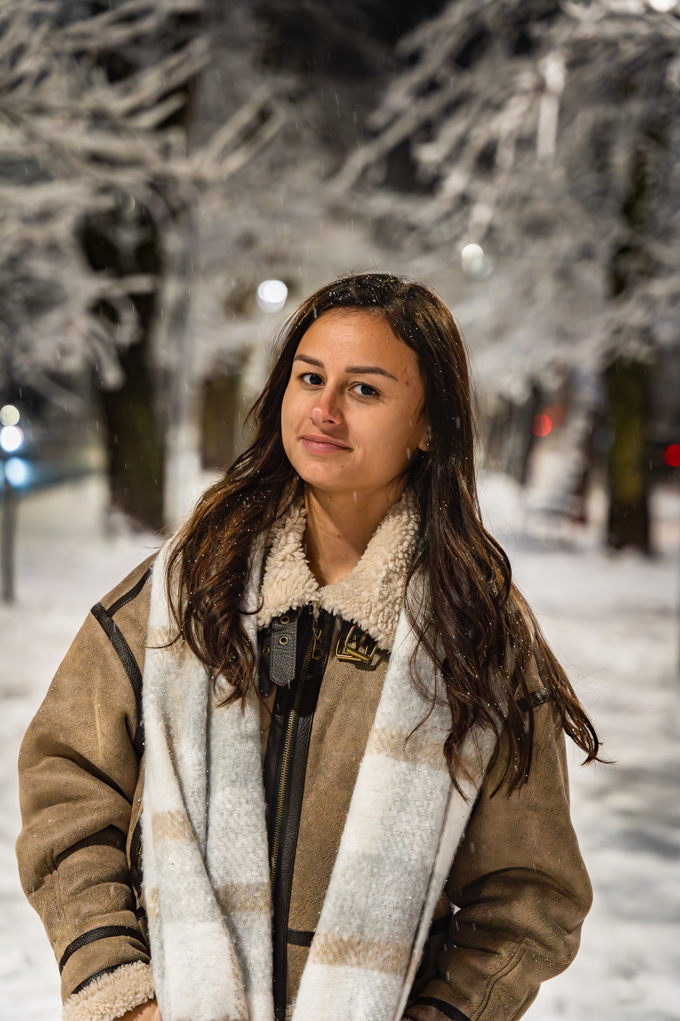 Nighttime winter lifestyle portrait of a brunette model in a shearling coat among frost-covered trees. Cinematic evening fashion photography by Arcane Media, UK.