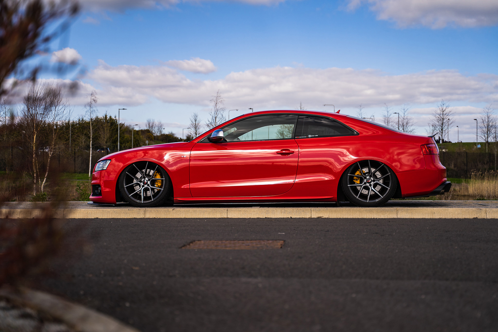 Red stanced Audi RS5 parked outdoors with cinematic natural lighting