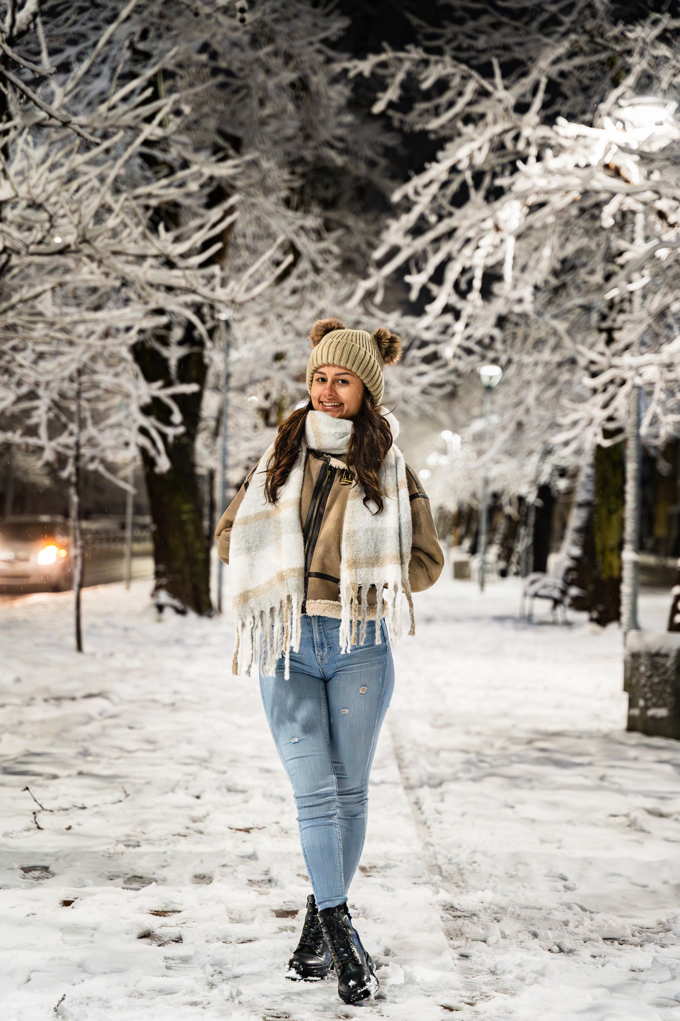 Full length night fashion portrait of a model in winter styling walking through a snow-covered park avenue. Editorial photography by Tenyo Barbolski, Cambridgeshire.