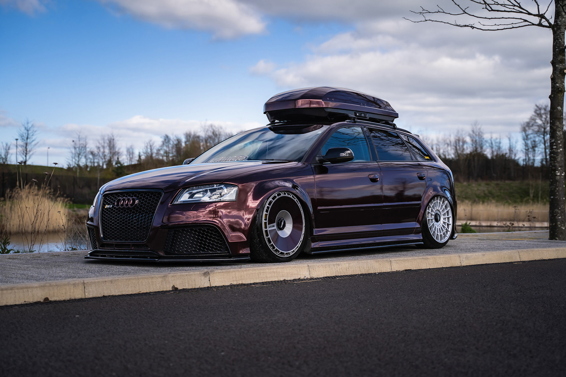Modified wagon car Audi RS3 with roof box parked in open outdoor space