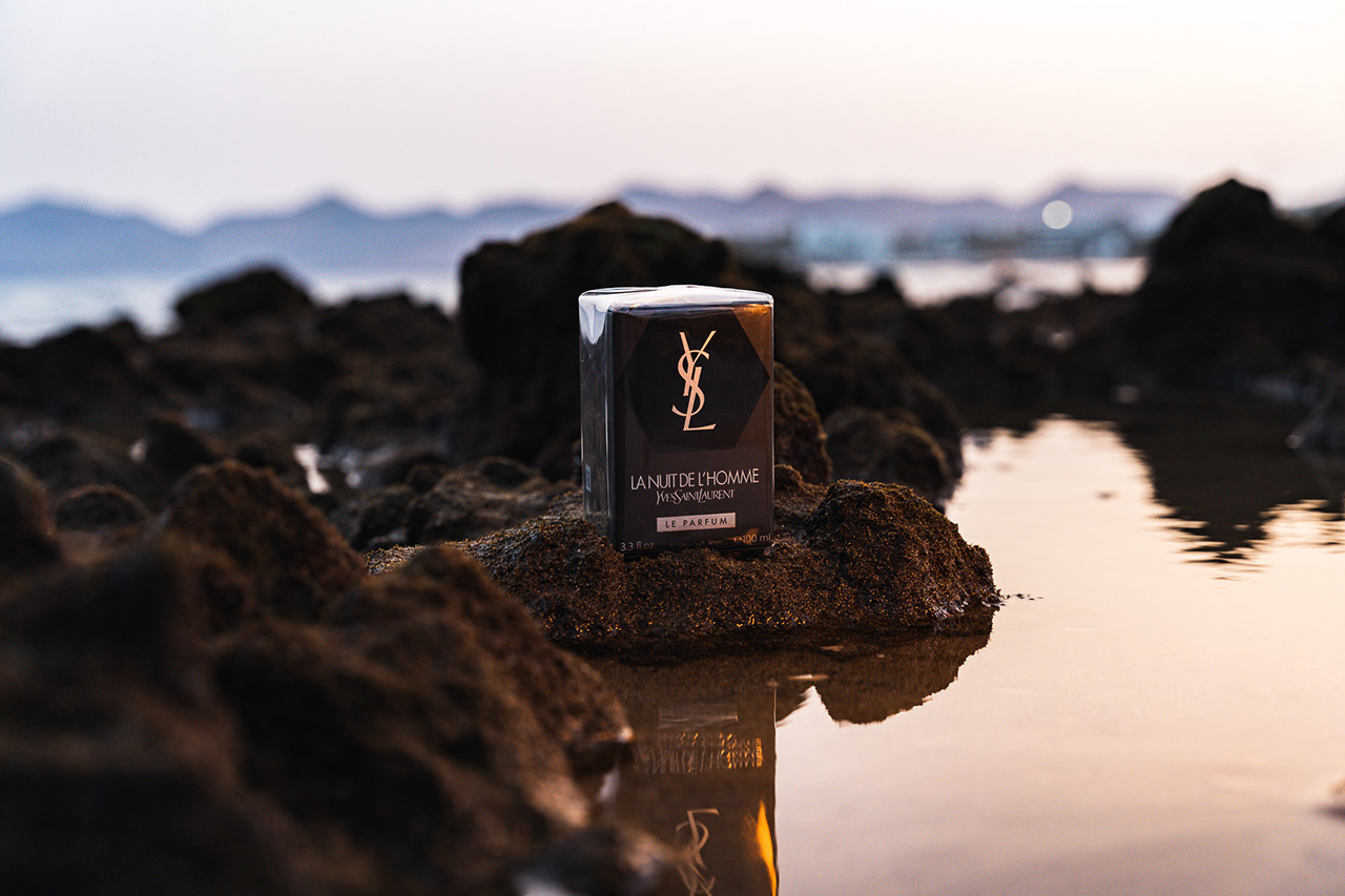 Precision macro product close-up of the textured Yves Saint Laurent (YSL) box on dark wet rocks. Highlighting luxury packaging materials and sharp branding details for commercial advertising. Arcane Media, Tenyo Barbolski."