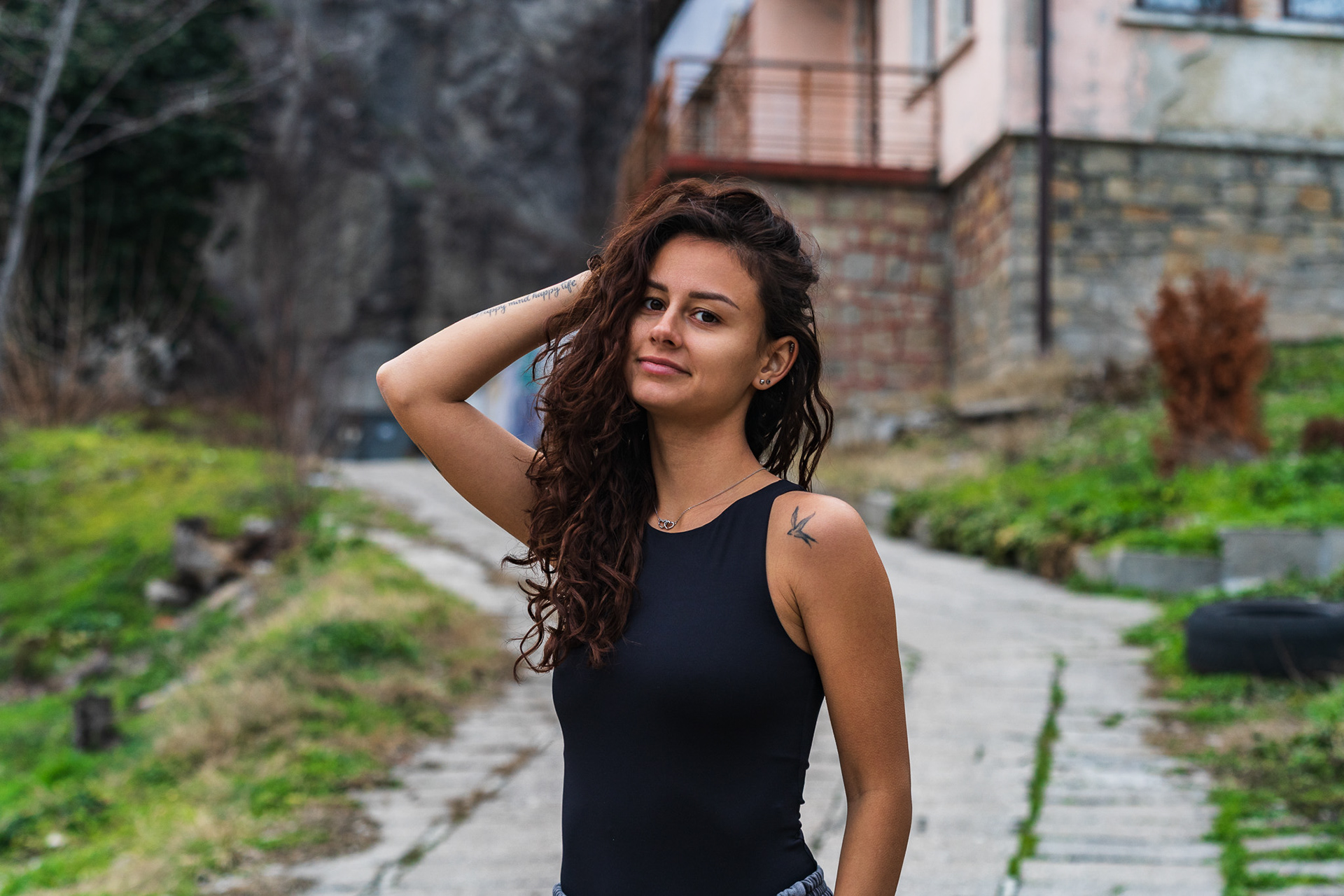 Outdoor lifestyle portrait of a brunette model on a stone pathway with lush green hillside backdrop. Natural light editorial photography by Arcane Media, UK