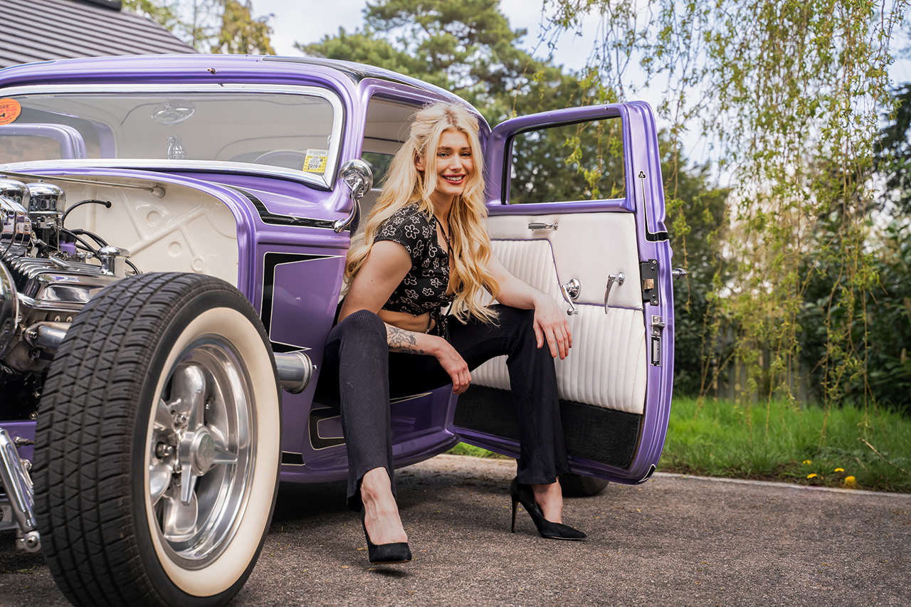 High-end vintage fashion photography featuring a blonde model with a custom purple Ford Model A hot rod. Capturing classic car culture, precise color correction, and pin-up styling. Specialized automotive portraiture by Tenyo Barbolski.