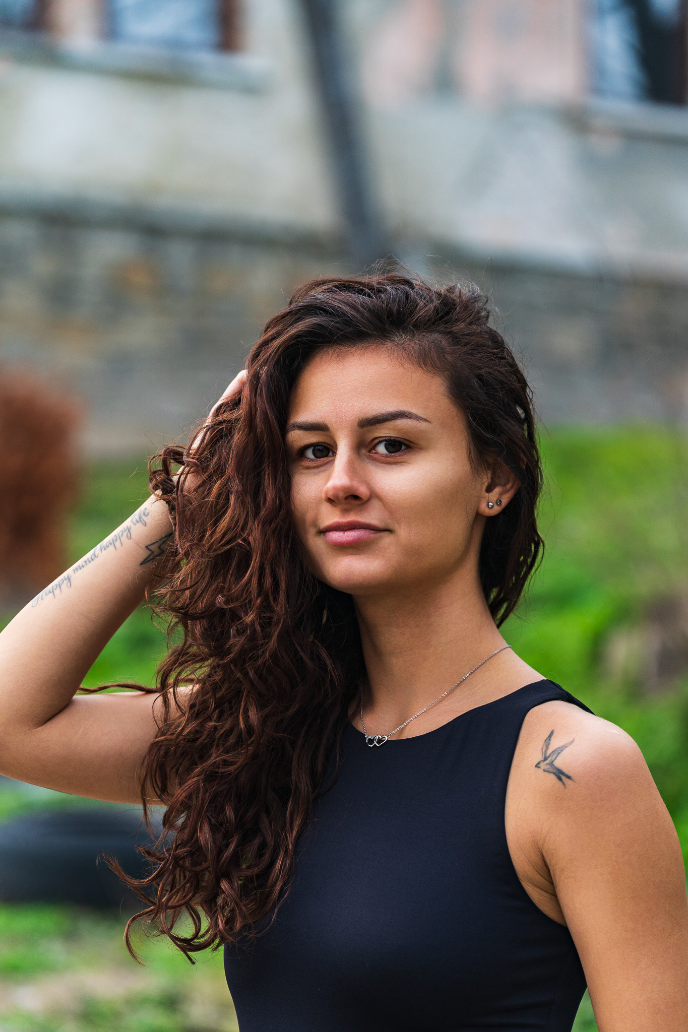 Editorial portrait of a curly haired model on a cobblestone path with historic stone building. Candid lifestyle photography by Tenyo Barbolski.